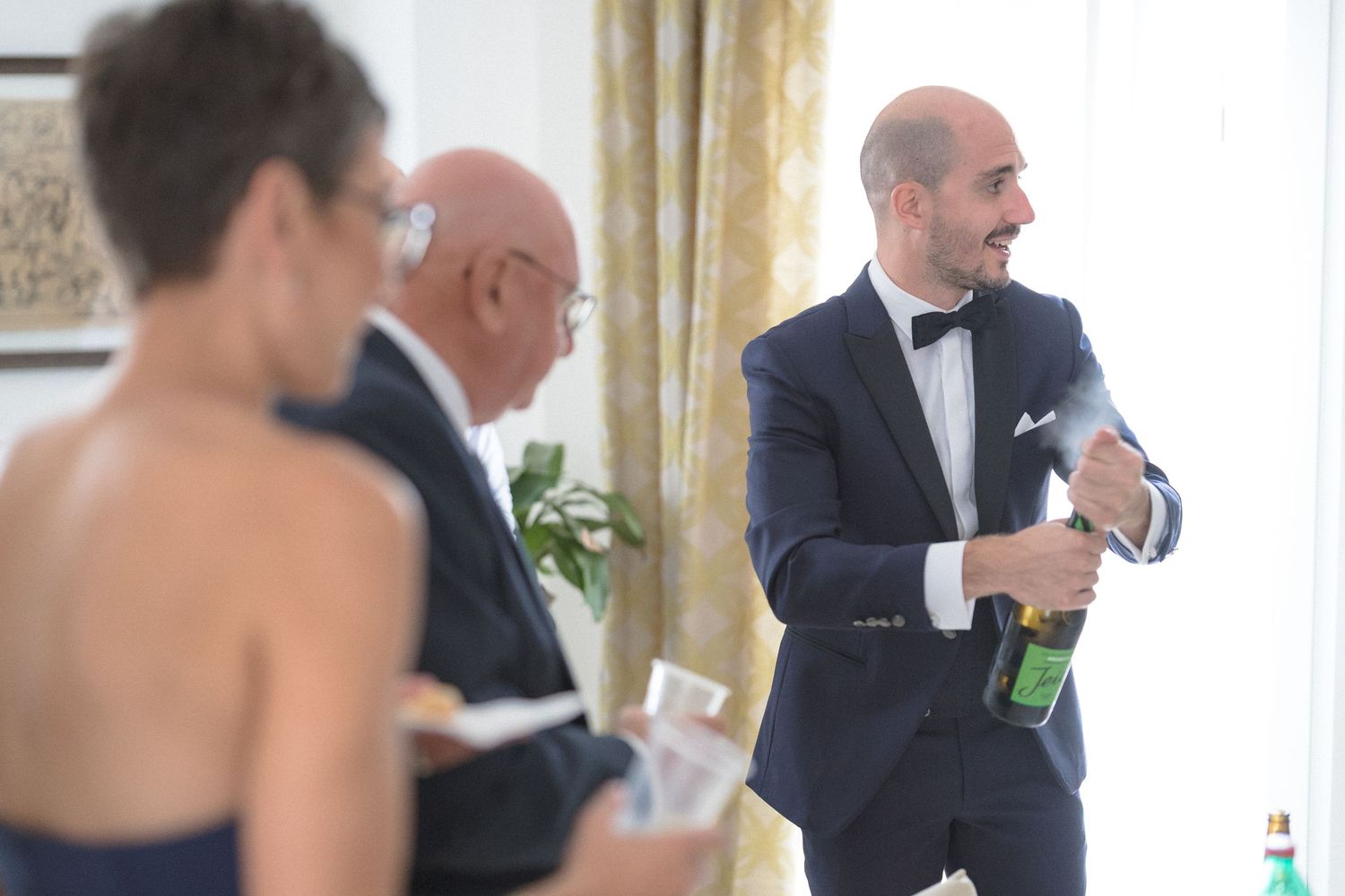 Wedding guests mingling in an elegant white and gold reception room.