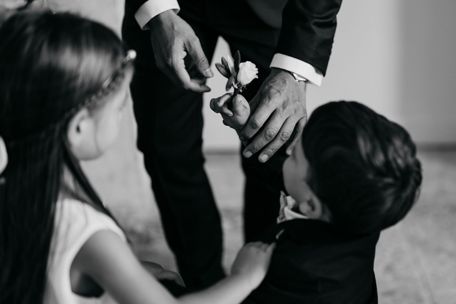 Close-up of hands helping children with formal attire adjustments.