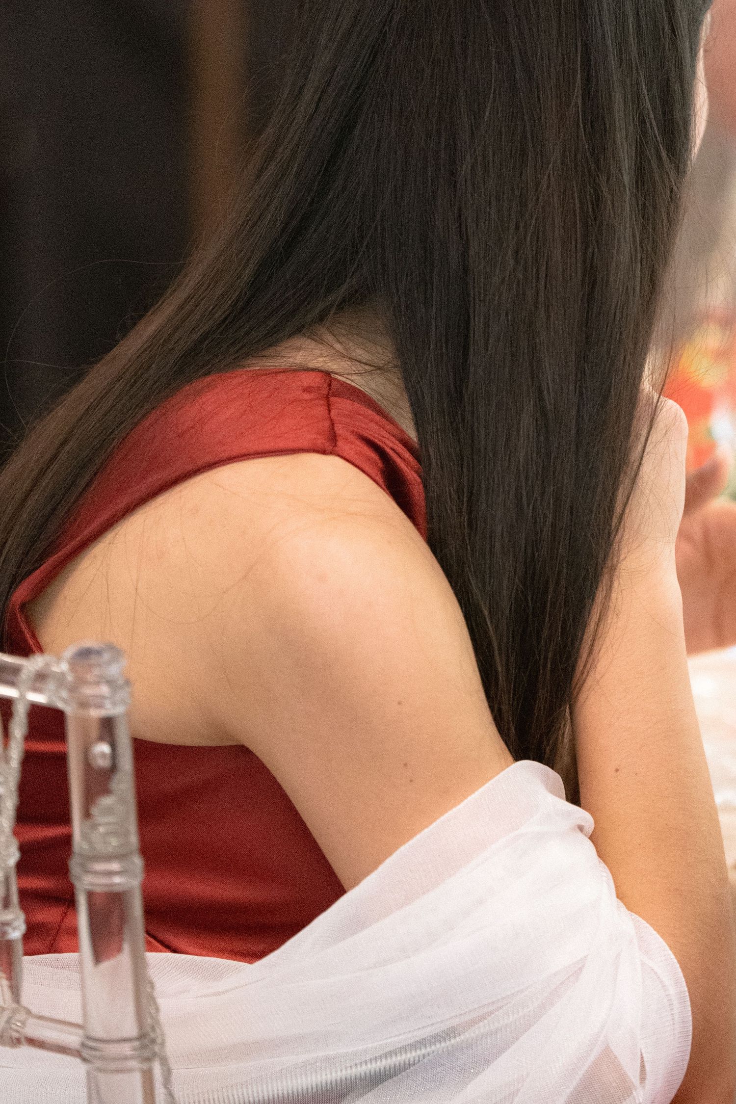 Close-up detail of a white and red formal dress against dark hair.
