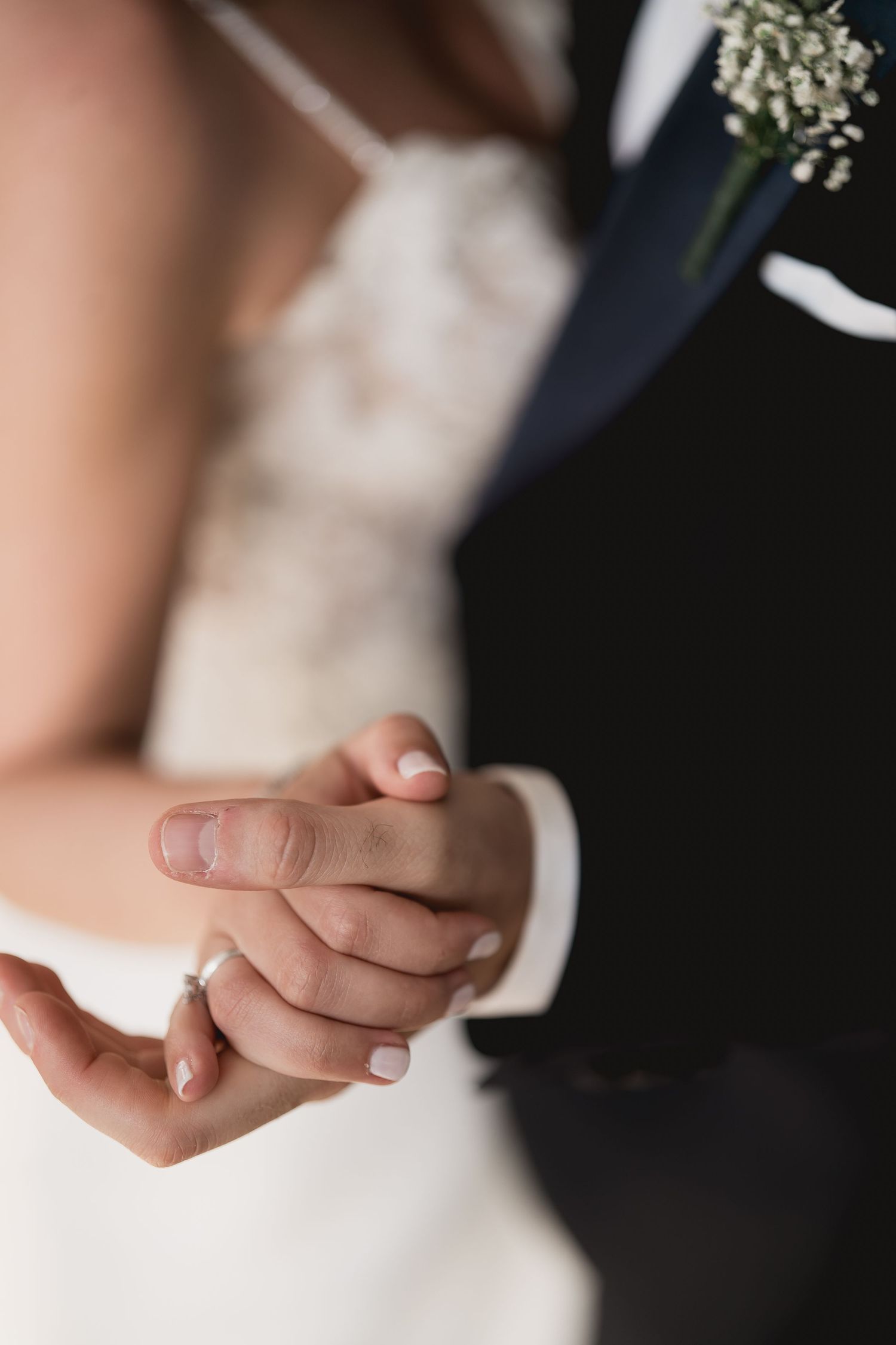 Close-up of clasped hands showing wedding rings during a romantic moment.