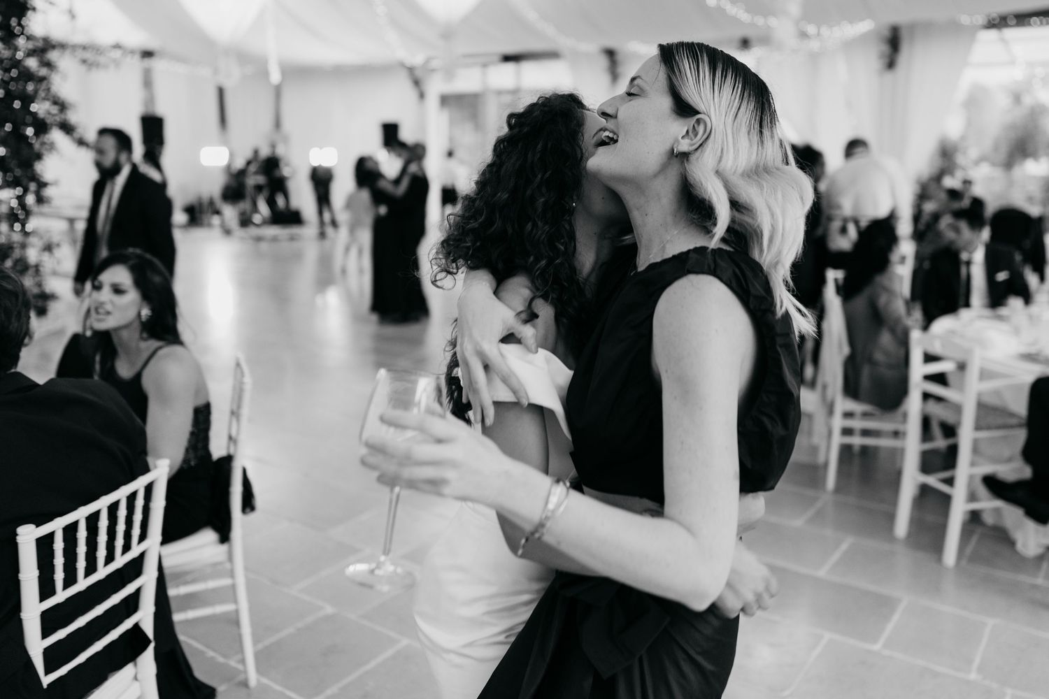 Wedding reception guests dancing and celebrating in an elegant white tent venue.