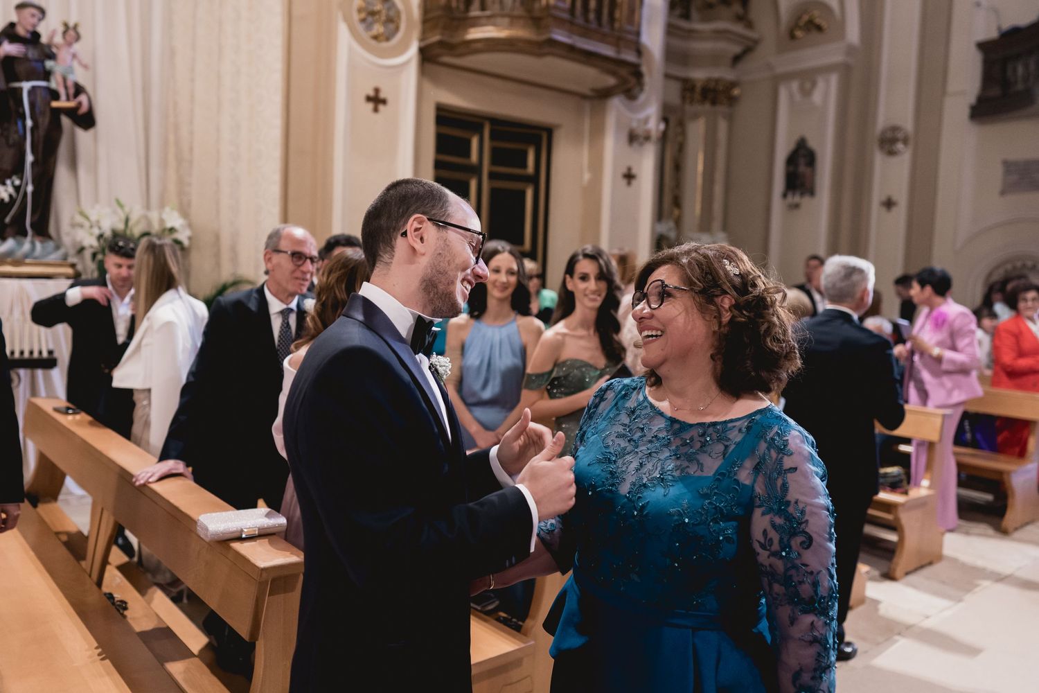 Wedding celebration inside ornate church with guests conversing.