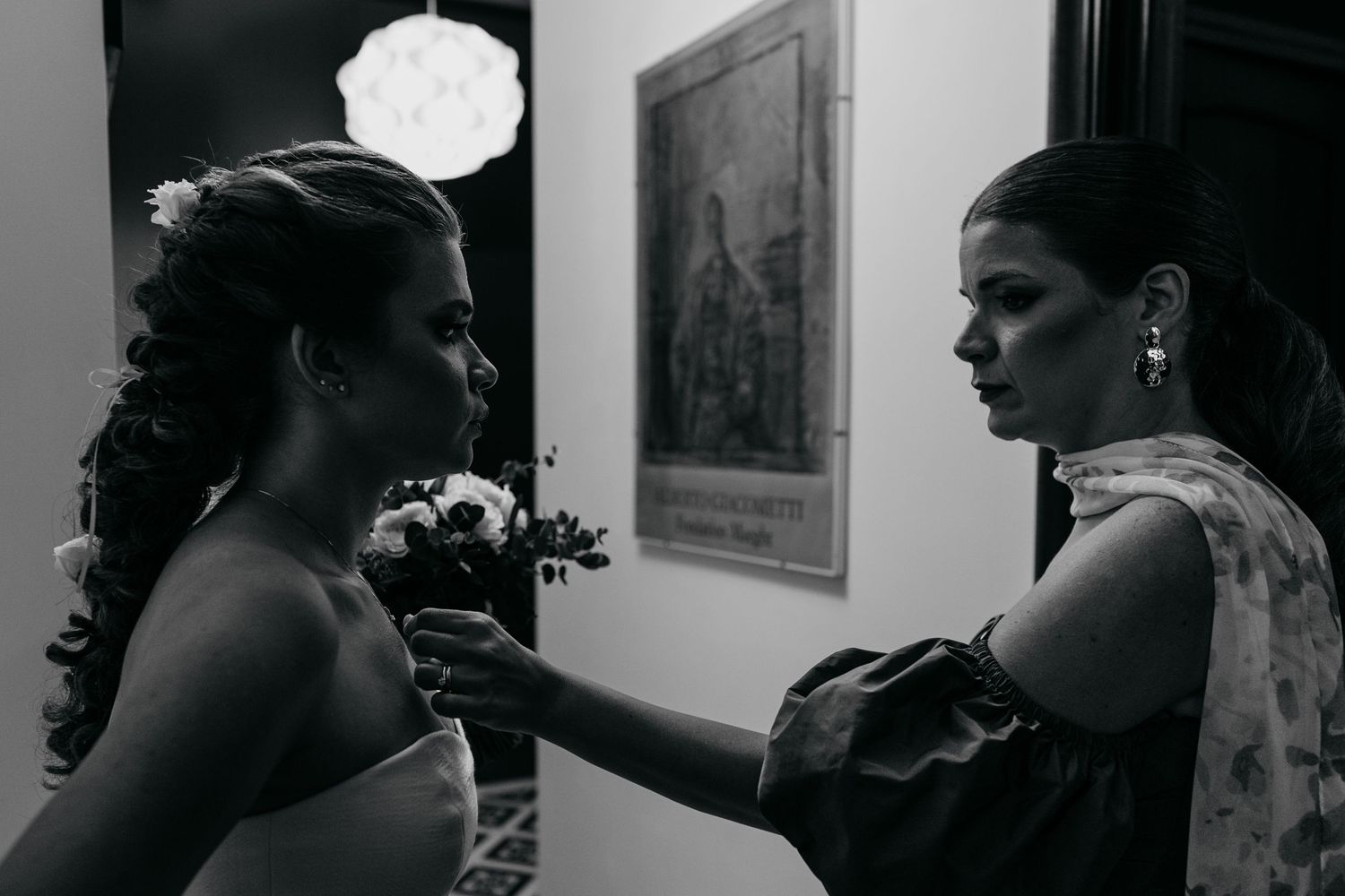 A tender moment captured in black and white as final adjustments are made to formal attire.