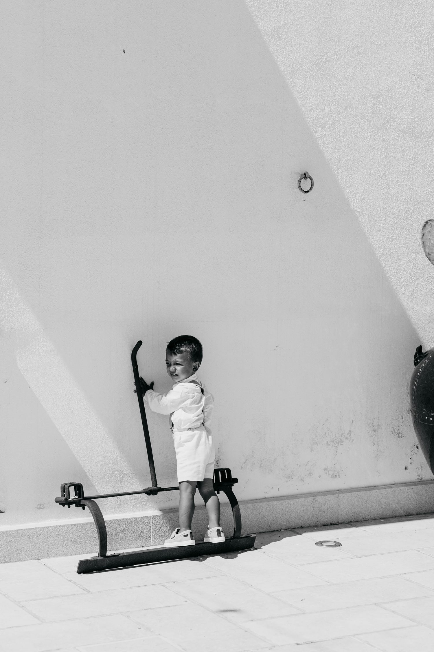Black and white sequence of child playing with shadow on white wall.
