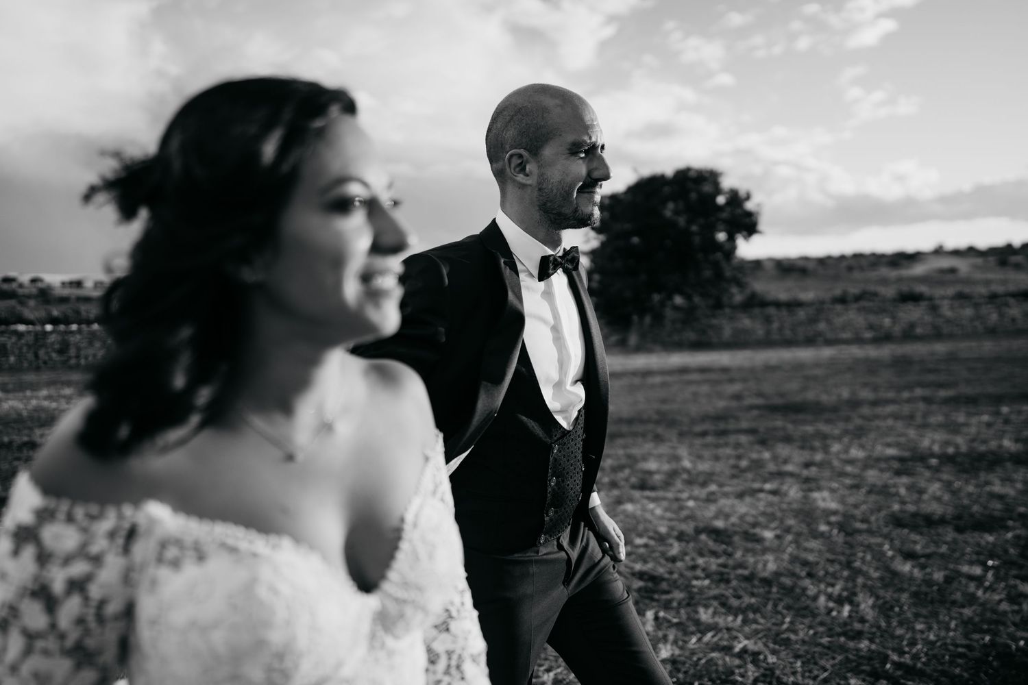 Dramatic black and white wedding portrait captured against a moody sky.