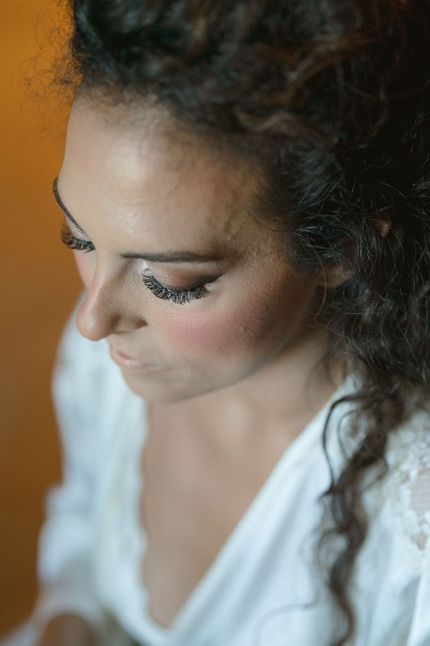 Close-up shot showing detailed eye makeup with long lashes and rosy cheeks.