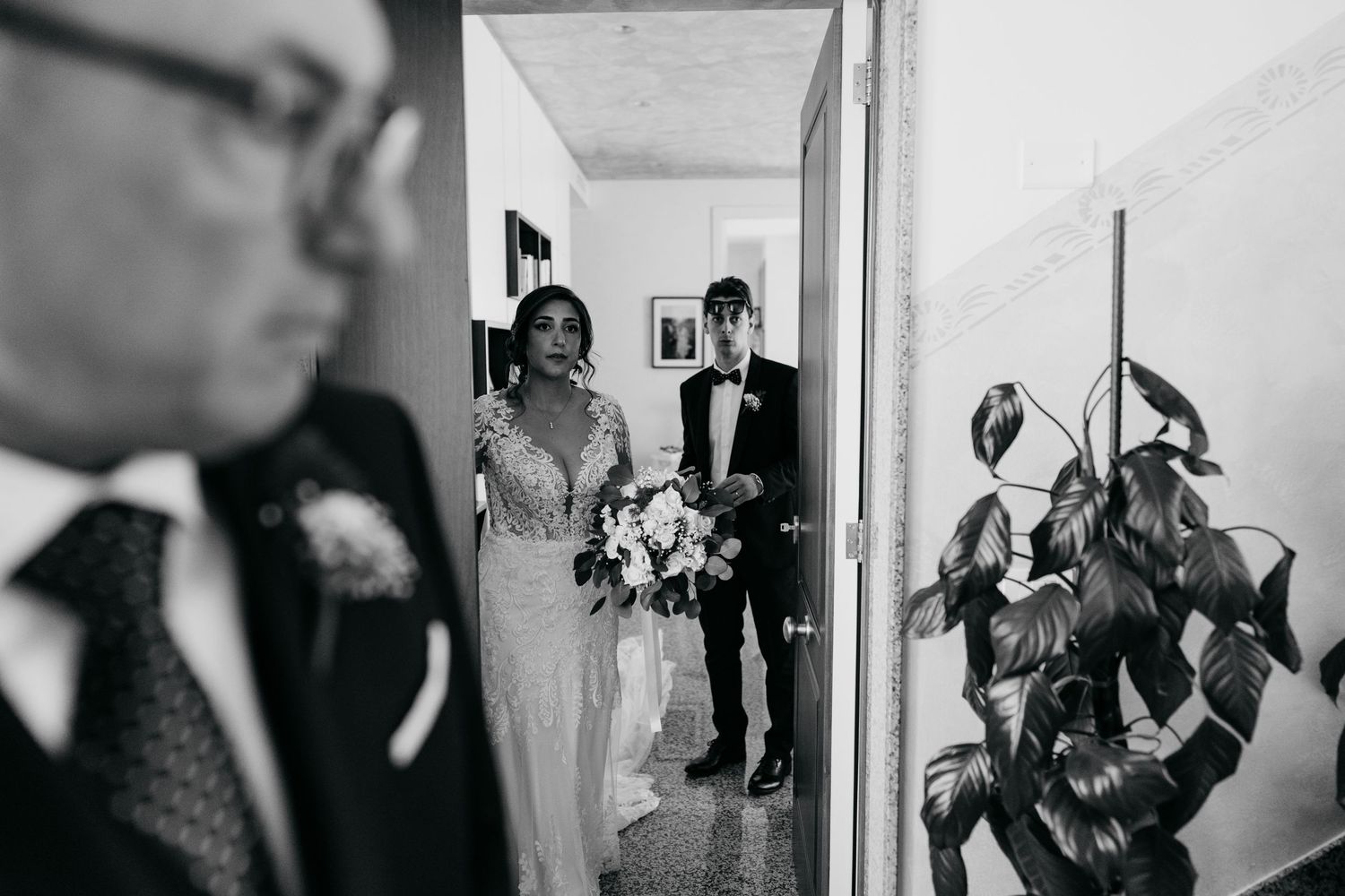 Black and white wedding preparation moments captured through doorways and hallways.