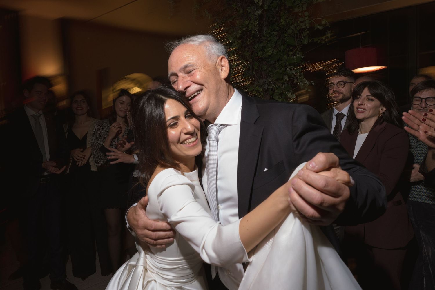 Bride and older man share a joyful dance together at a wedding reception celebration.
