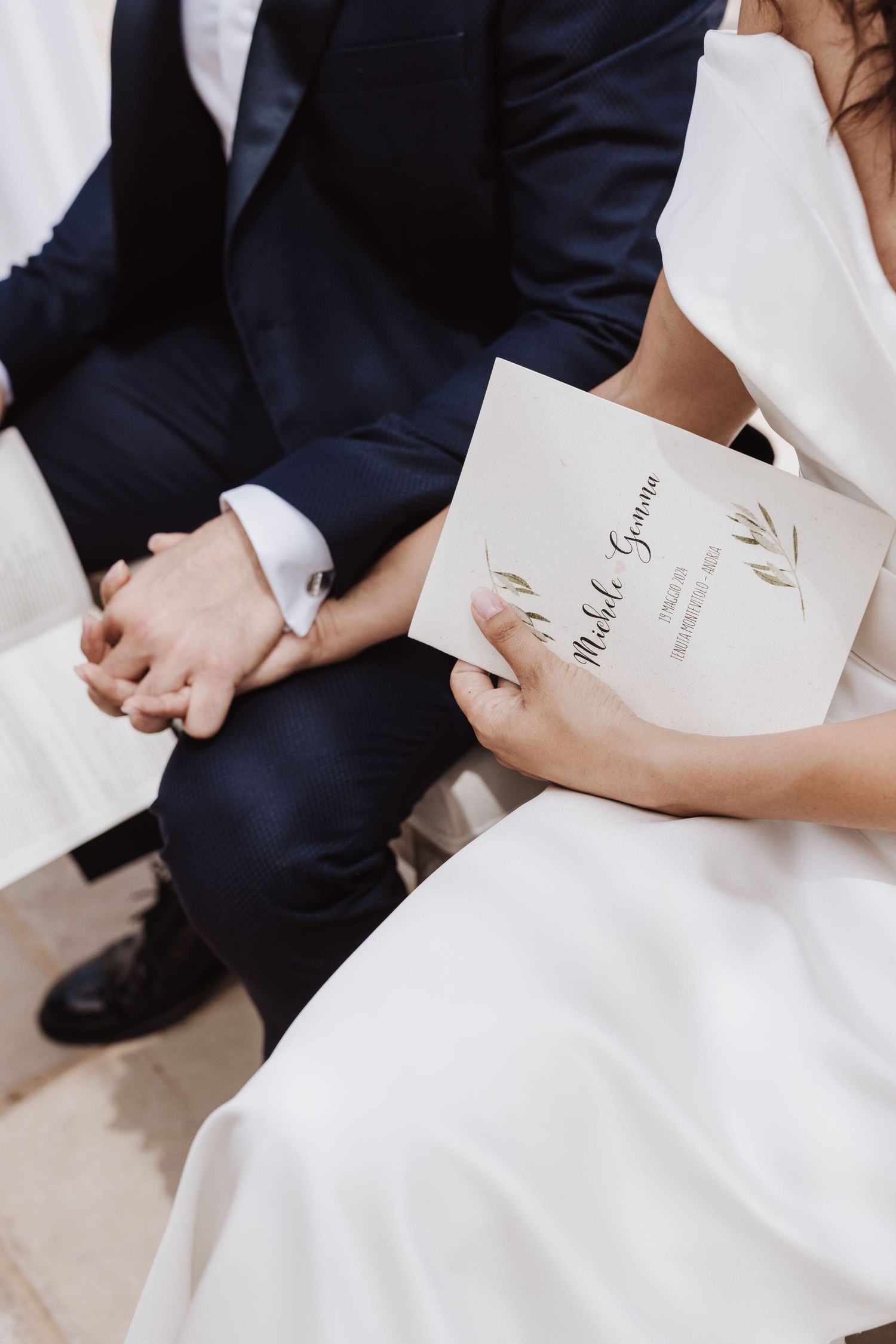 Close-up of couple holding order of service during wedding ceremony.