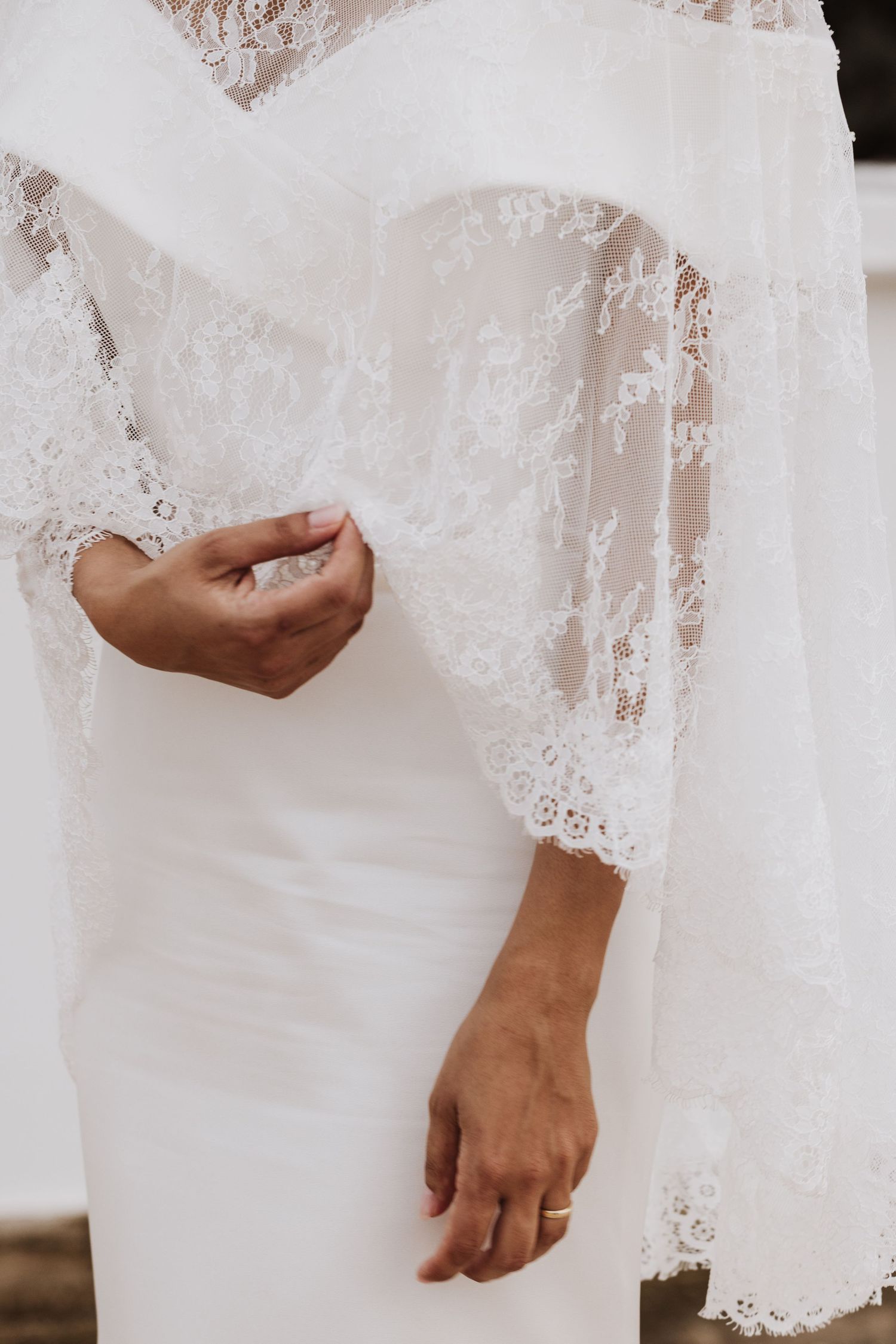 Close-up of elegant wedding dress showing intricate lace sleeve and bodice details.