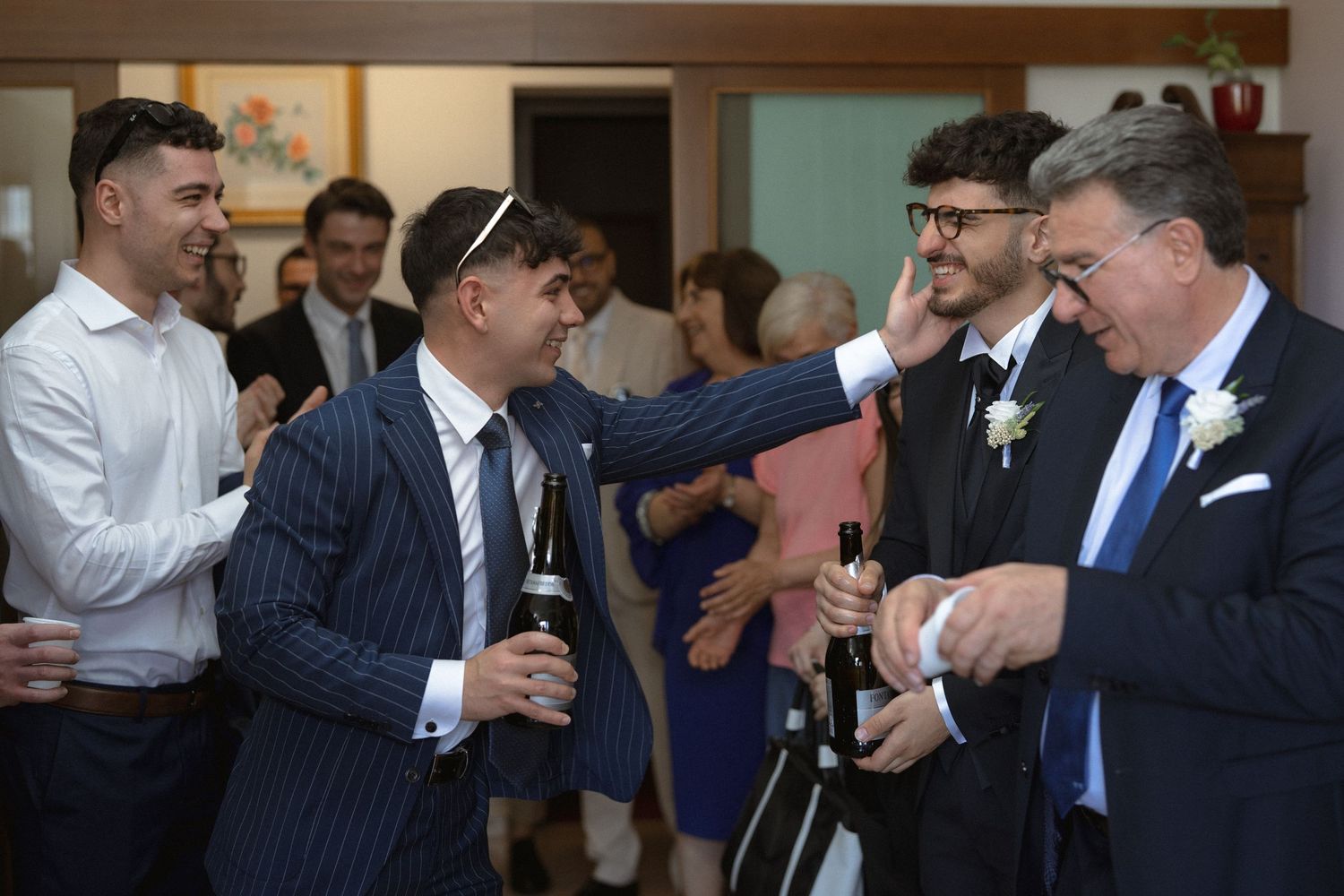 A group of well-dressed people in suits and formal attire enjoying drinks and conversation at a social gathering.