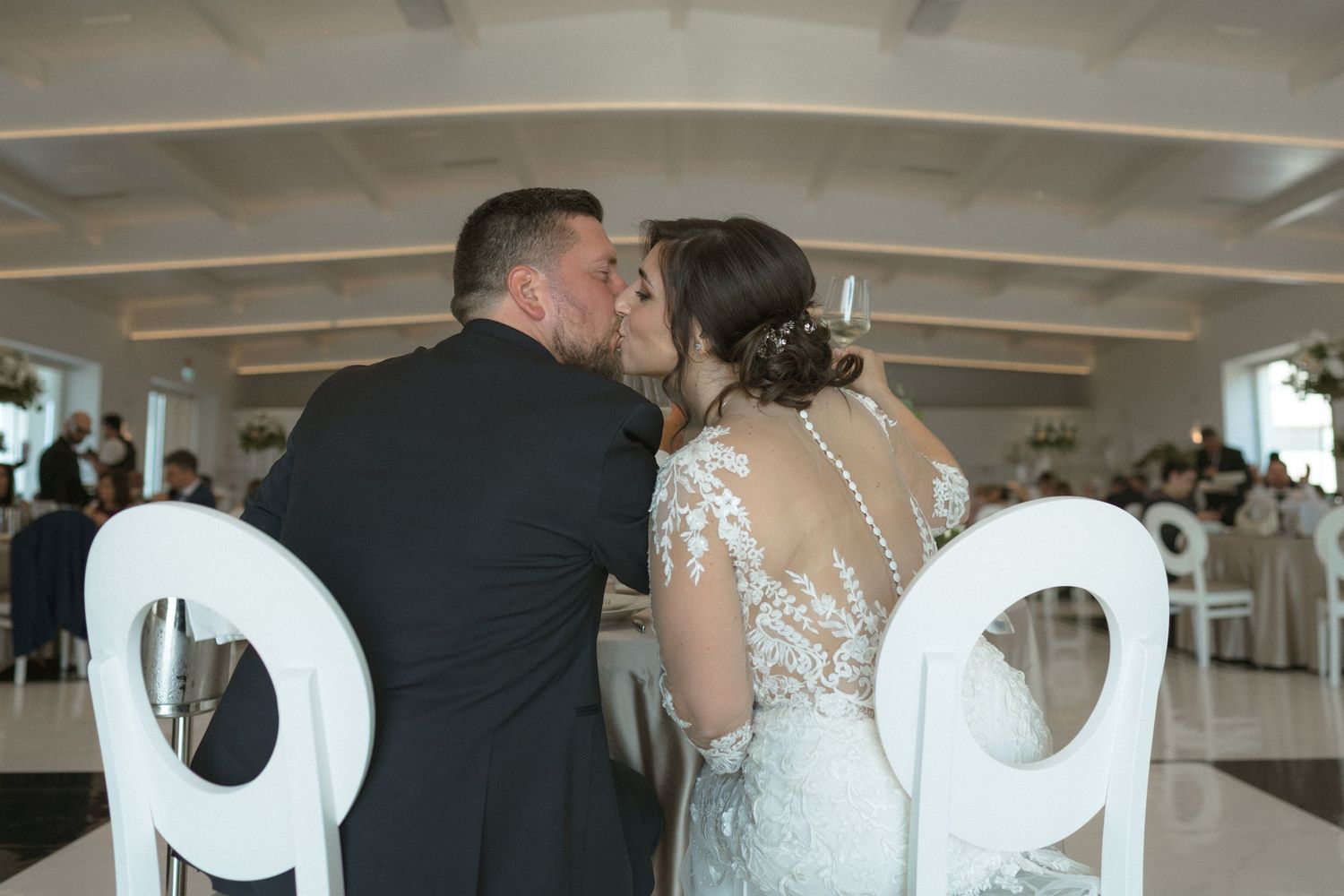 Wedding ceremony setup with white chairs and decorative elements in an elegant indoor venue.