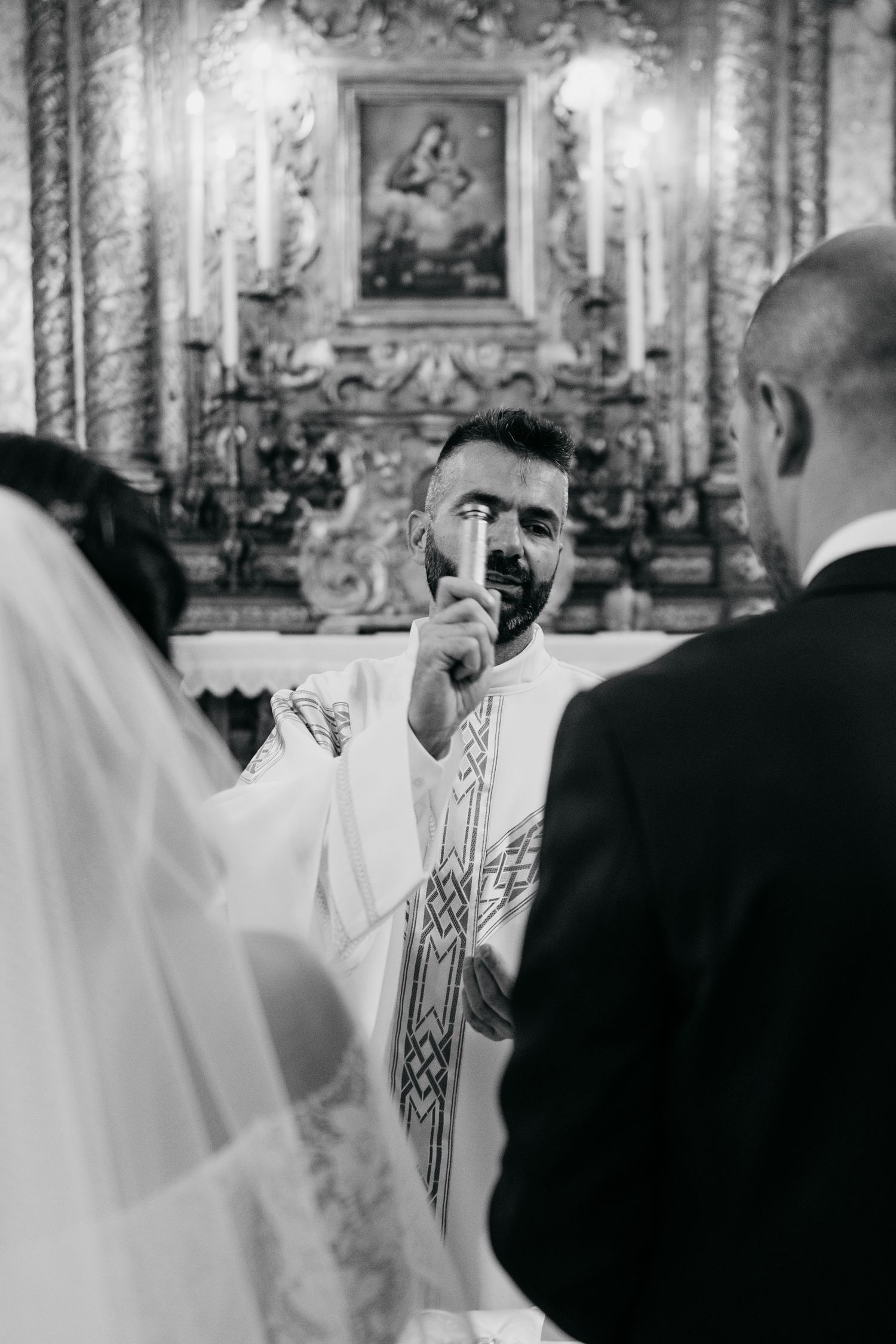 A religious ceremony takes place inside an ornate church with decorative walls and architectural details.