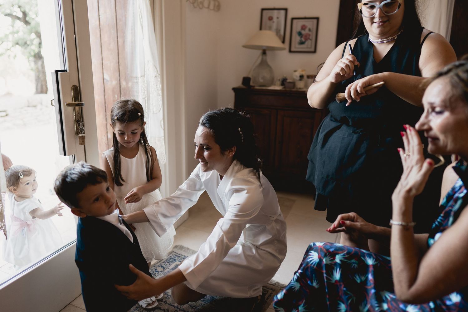 A busy scene of wedding day preparations in a sunlit room.