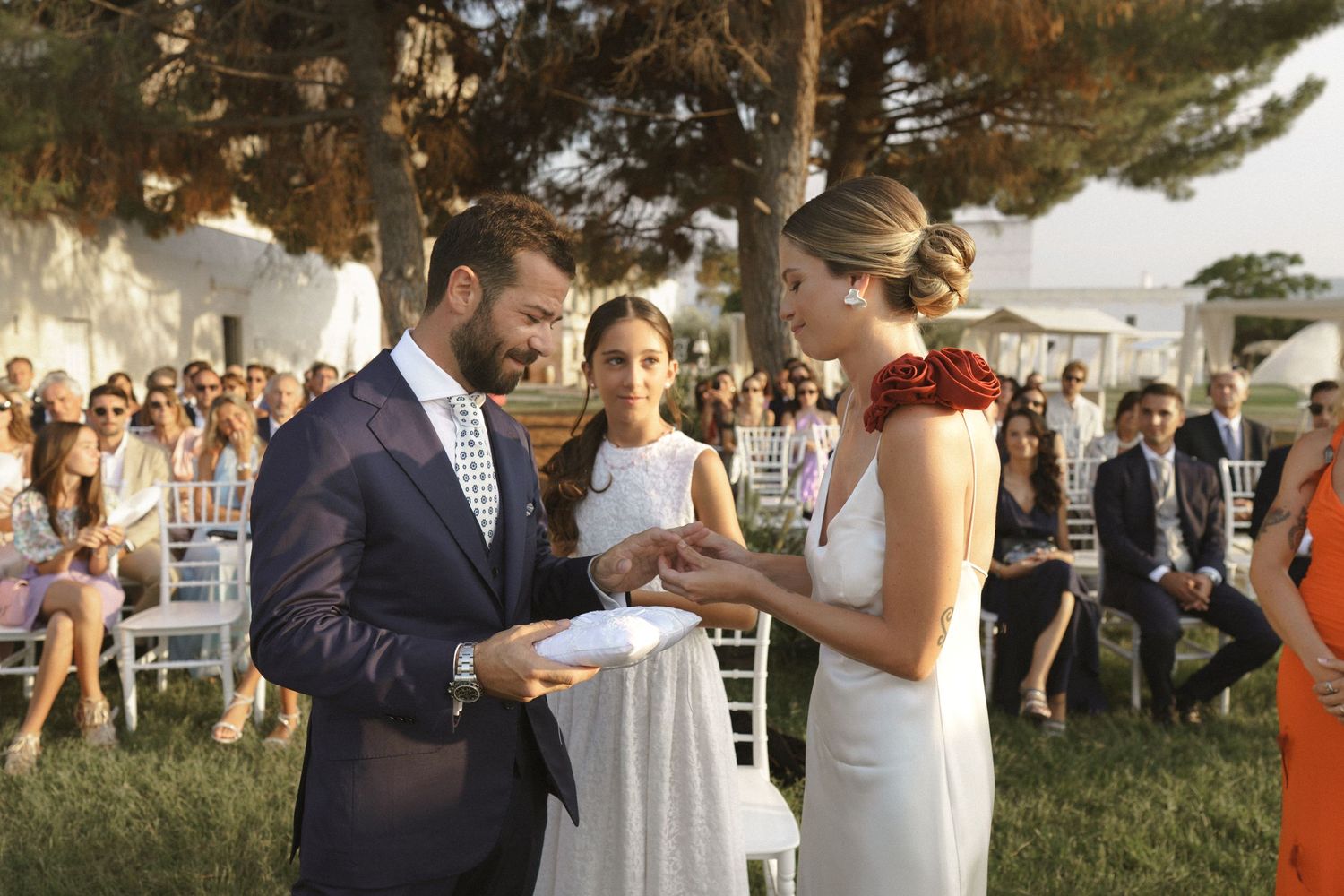 A couple exchanges wedding vows during an intimate outdoor ceremony surrounded by guests.