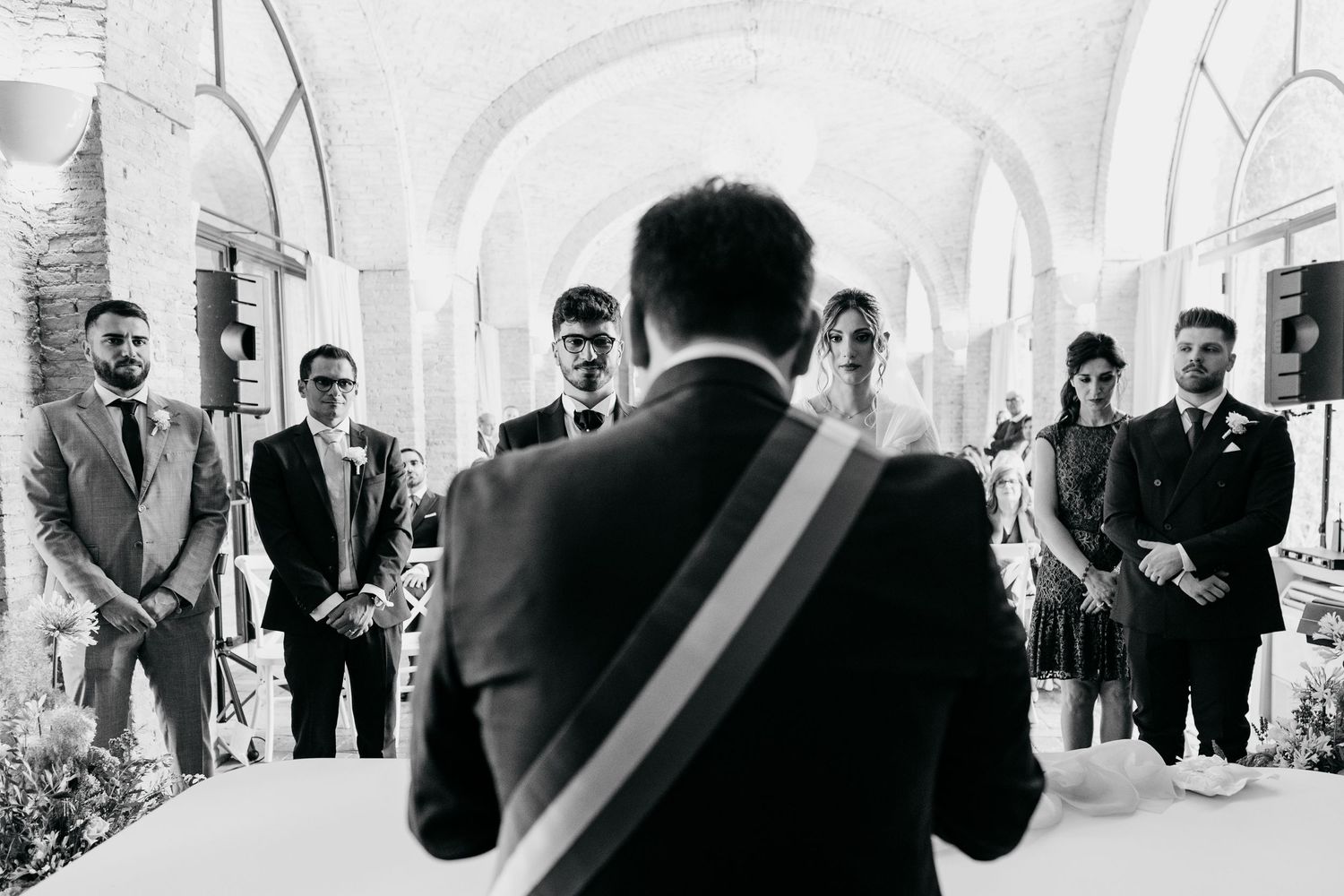 Wedding celebration candid moments captured in a bright, arched corridor.