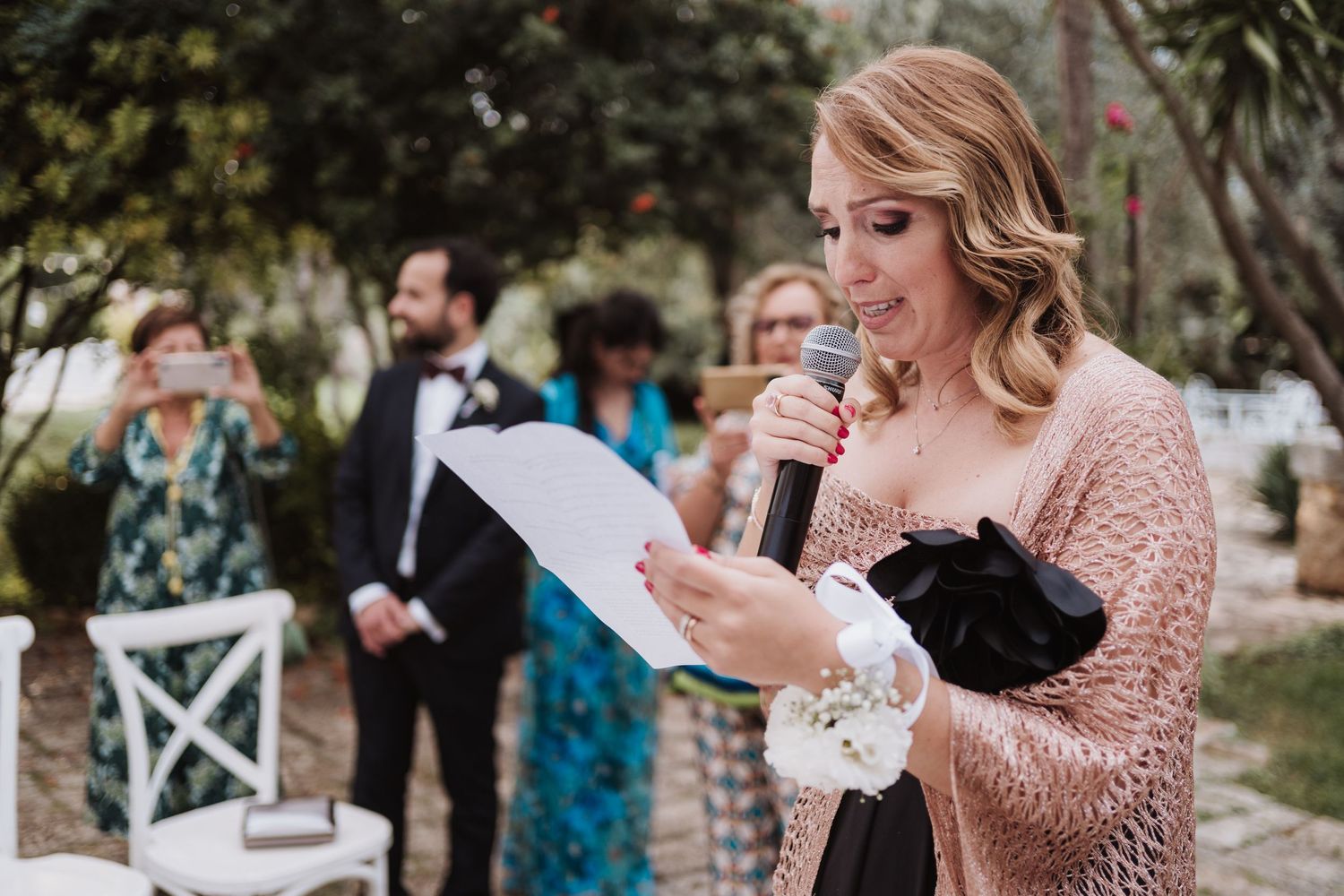 Wedding guest delivers an emotional speech at outdoor ceremony while holding papers.