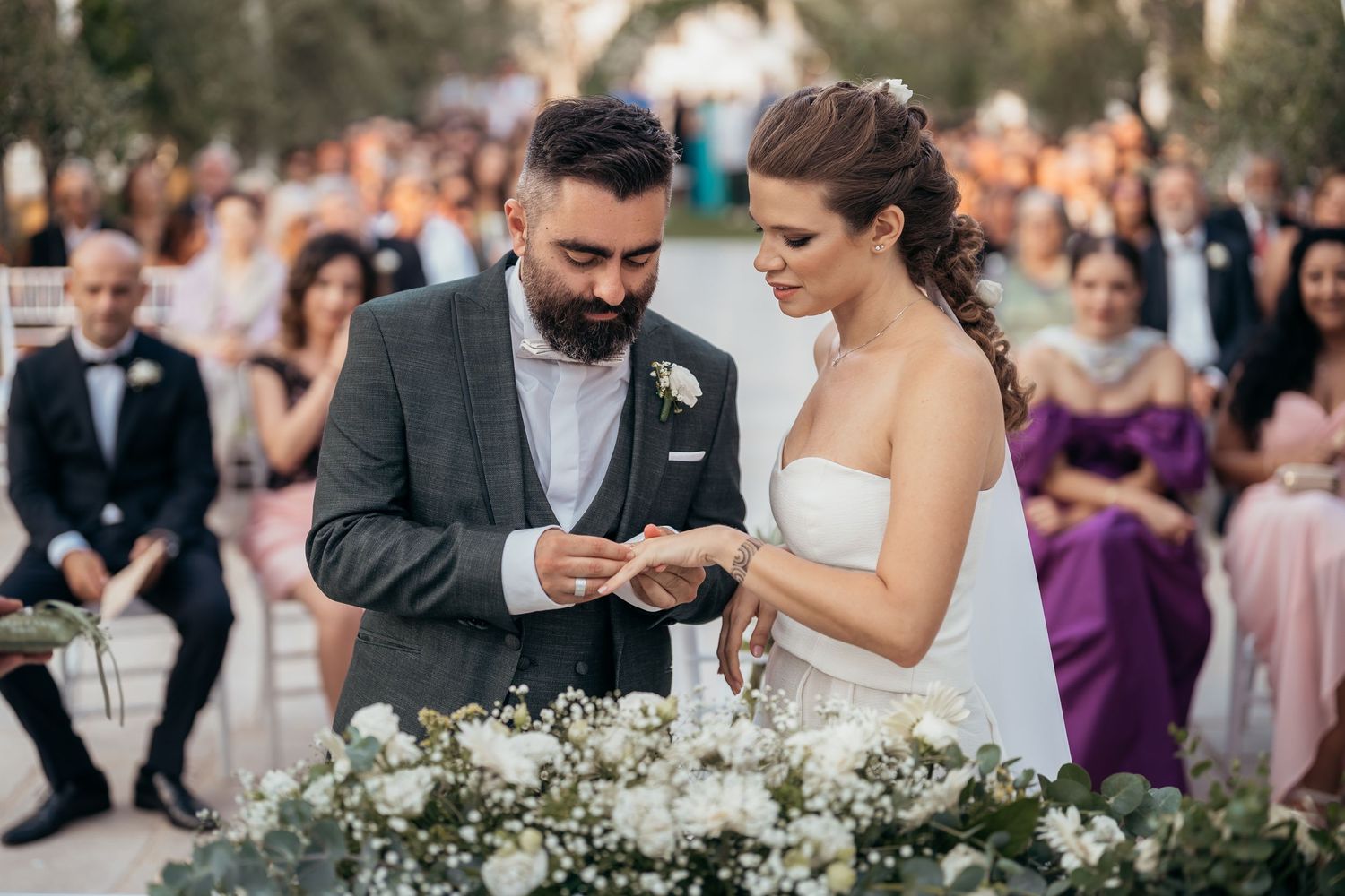 Wedding ceremony moment with couple exchanging rings at decorated outdoor altar.