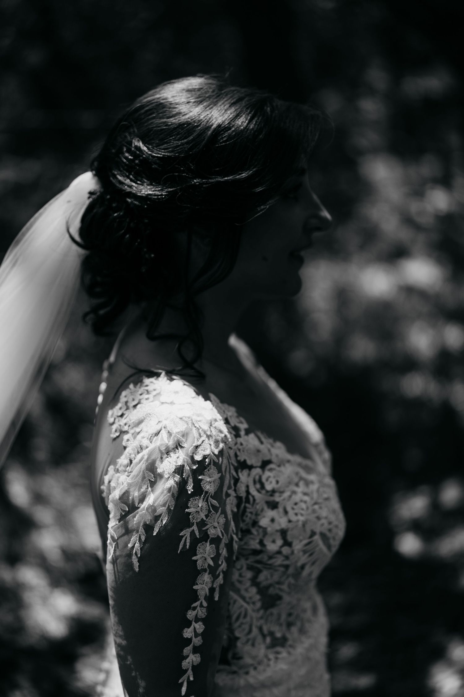Close-up details of delicate lace wedding dress with intricate floral patterns in black and white.