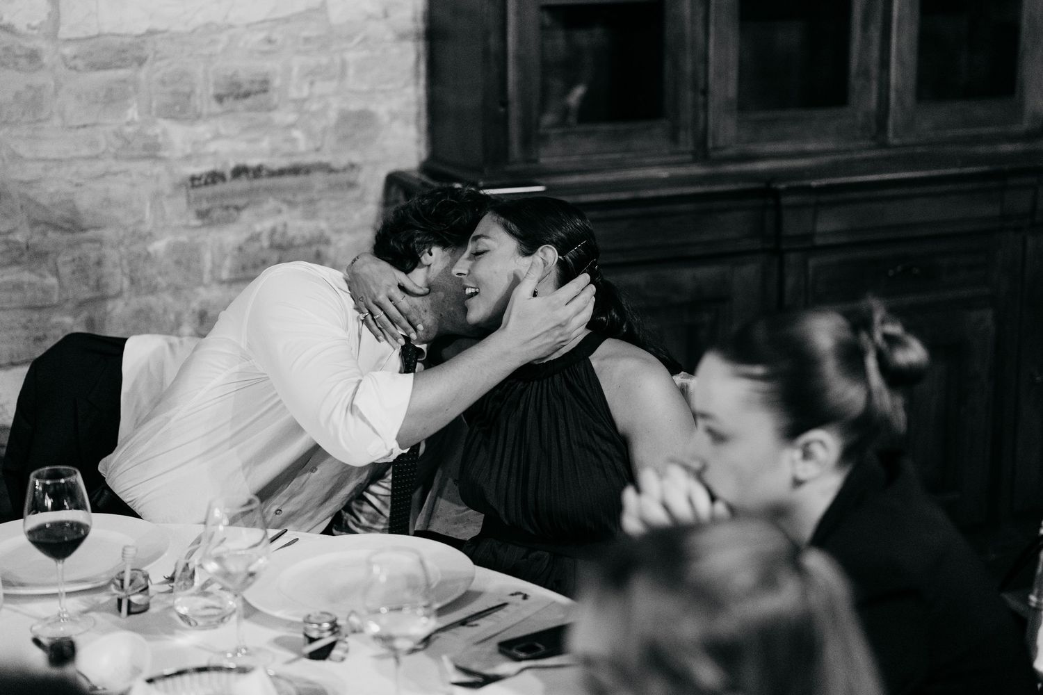 A black and white photo series showing a couple sharing a romantic kiss at their wedding ceremony.