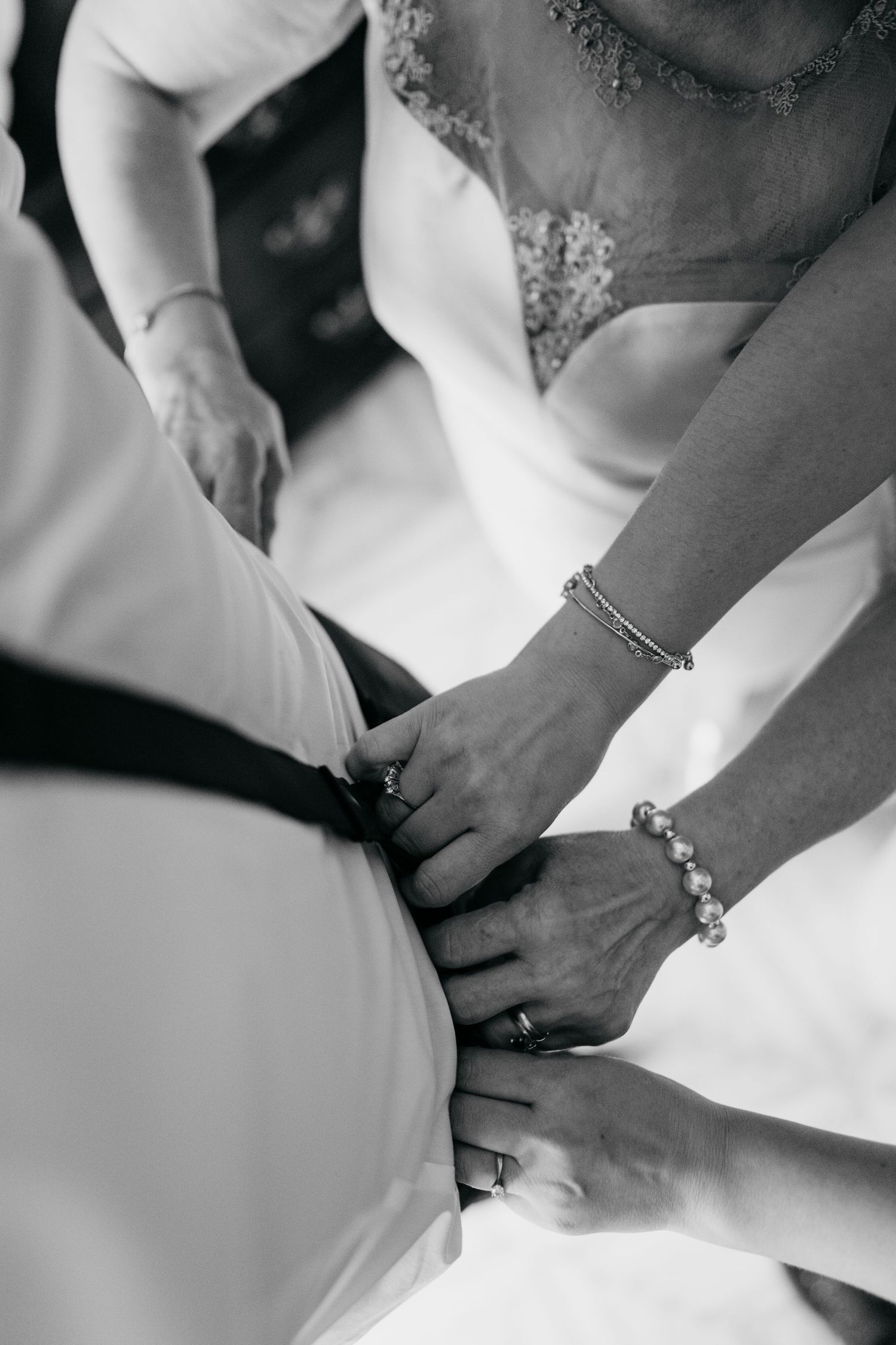 Close-up shots of hands holding and adjusting jewelry in black and white.