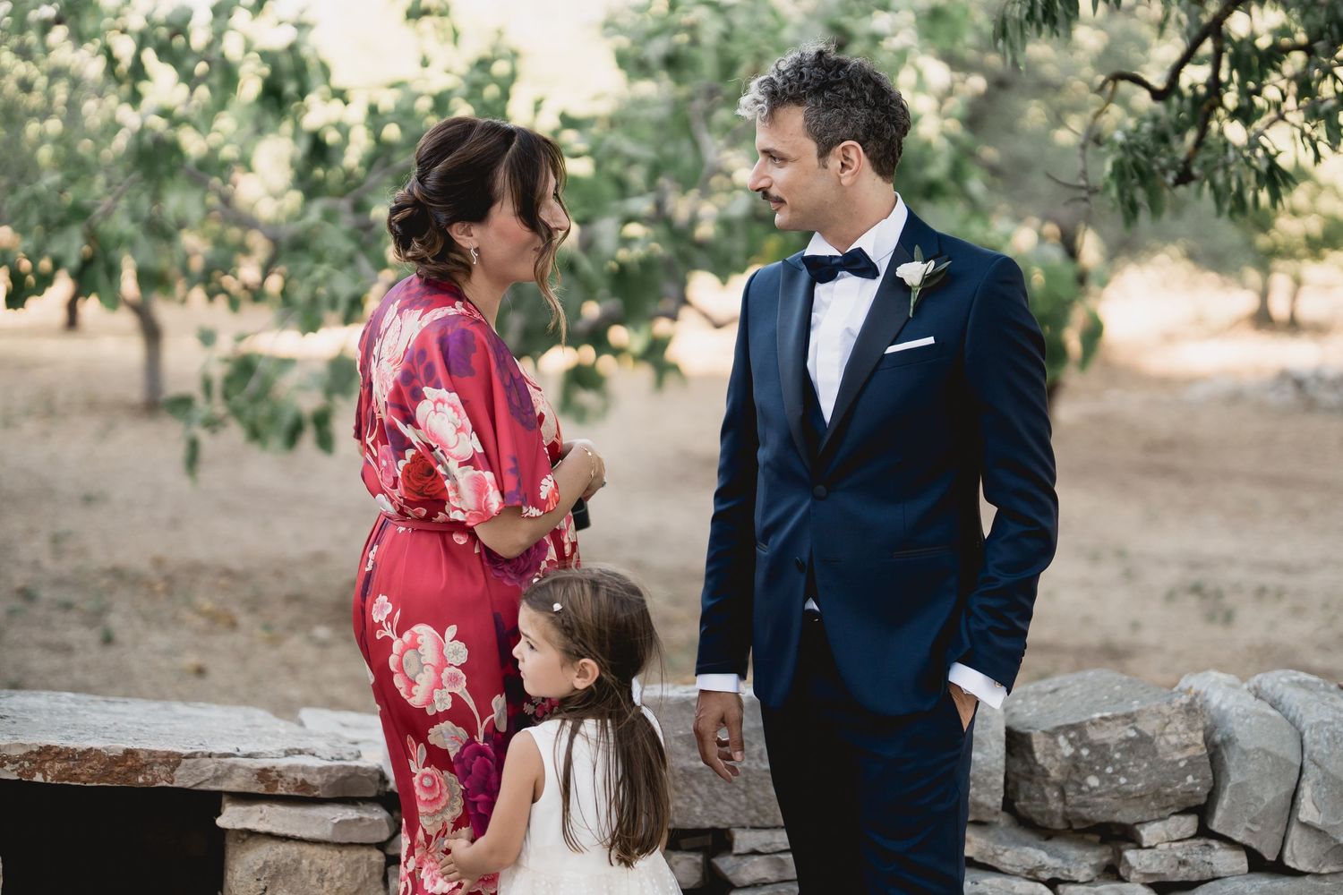 A wedding scene featuring formal attire and a pink floral kimono in a rustic outdoor setting.