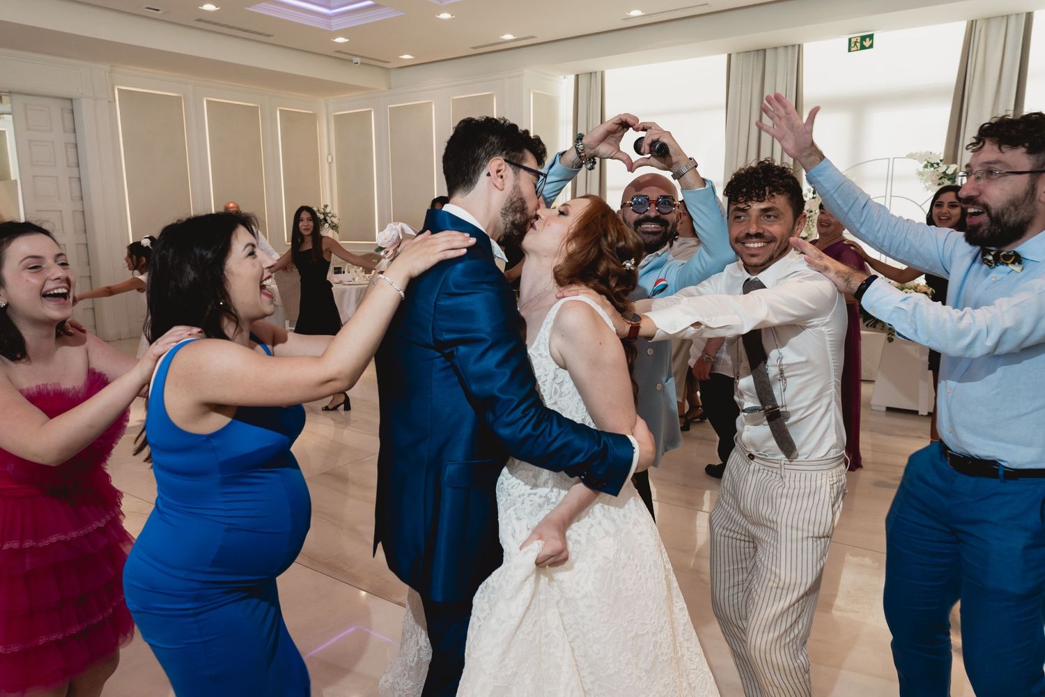 Wedding party celebrates joyfully on the dance floor during reception festivities.