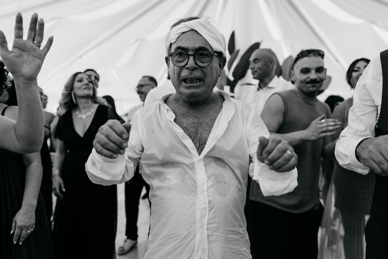 Wedding guests dancing and celebrating with raised hands at a reception party.
