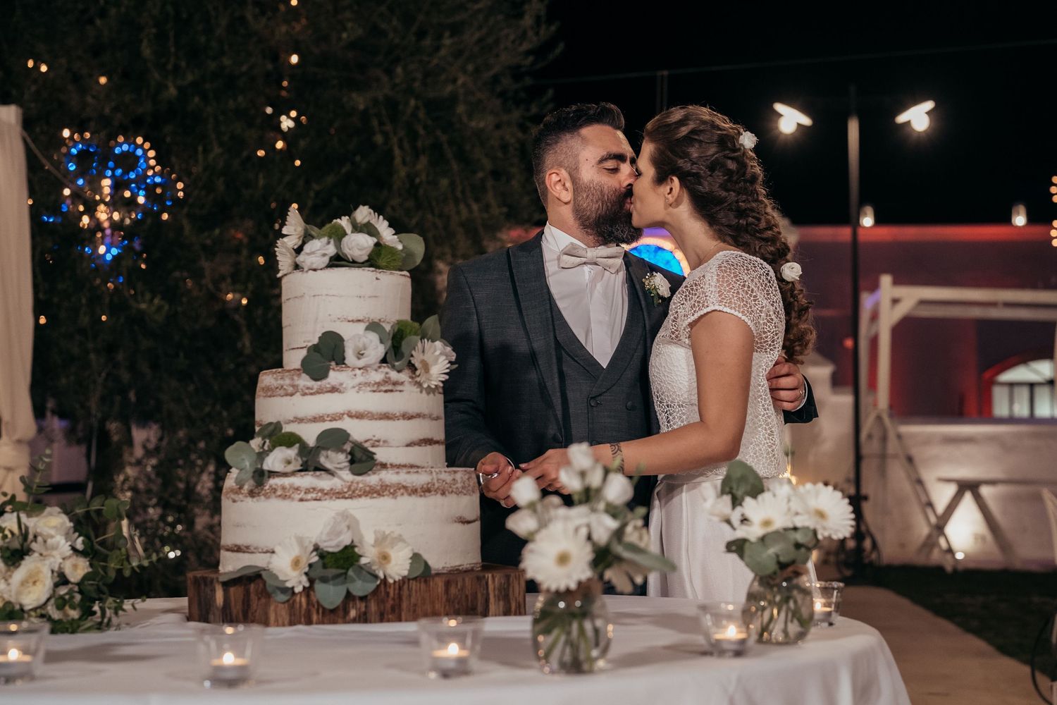 Elegant wedding cake display with floral decorations as couple shares intimate moment.