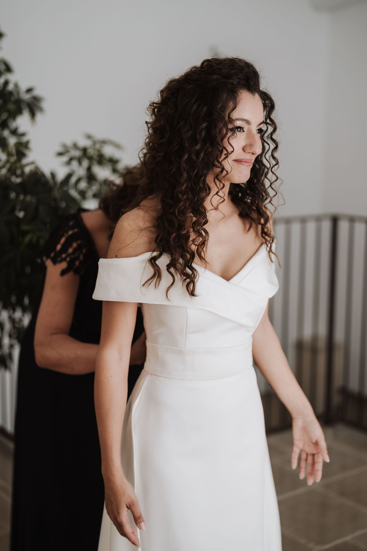 A bride wearing an elegant off-shoulder white wedding dress poses before the ceremony.