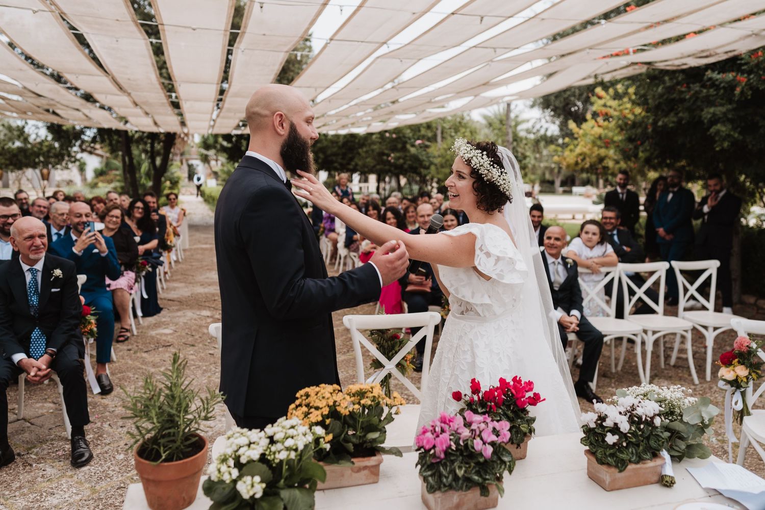 Outdoor wedding ceremony with floral decorations and rustic wooden pergola.