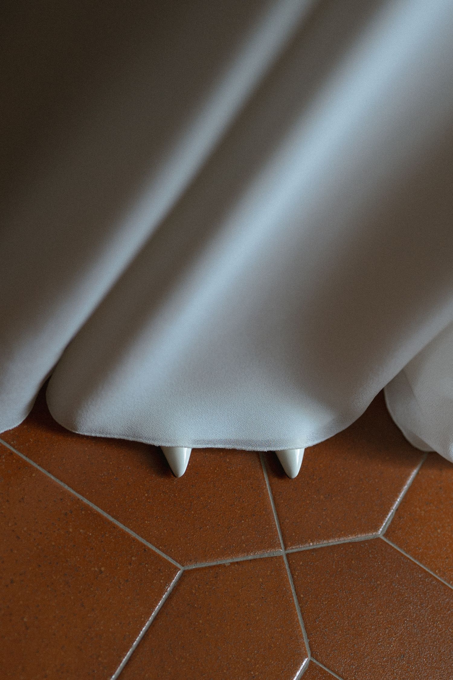 White curtain fabric creates soft diagonal lines against a brown wooden surface in dramatic lighting.