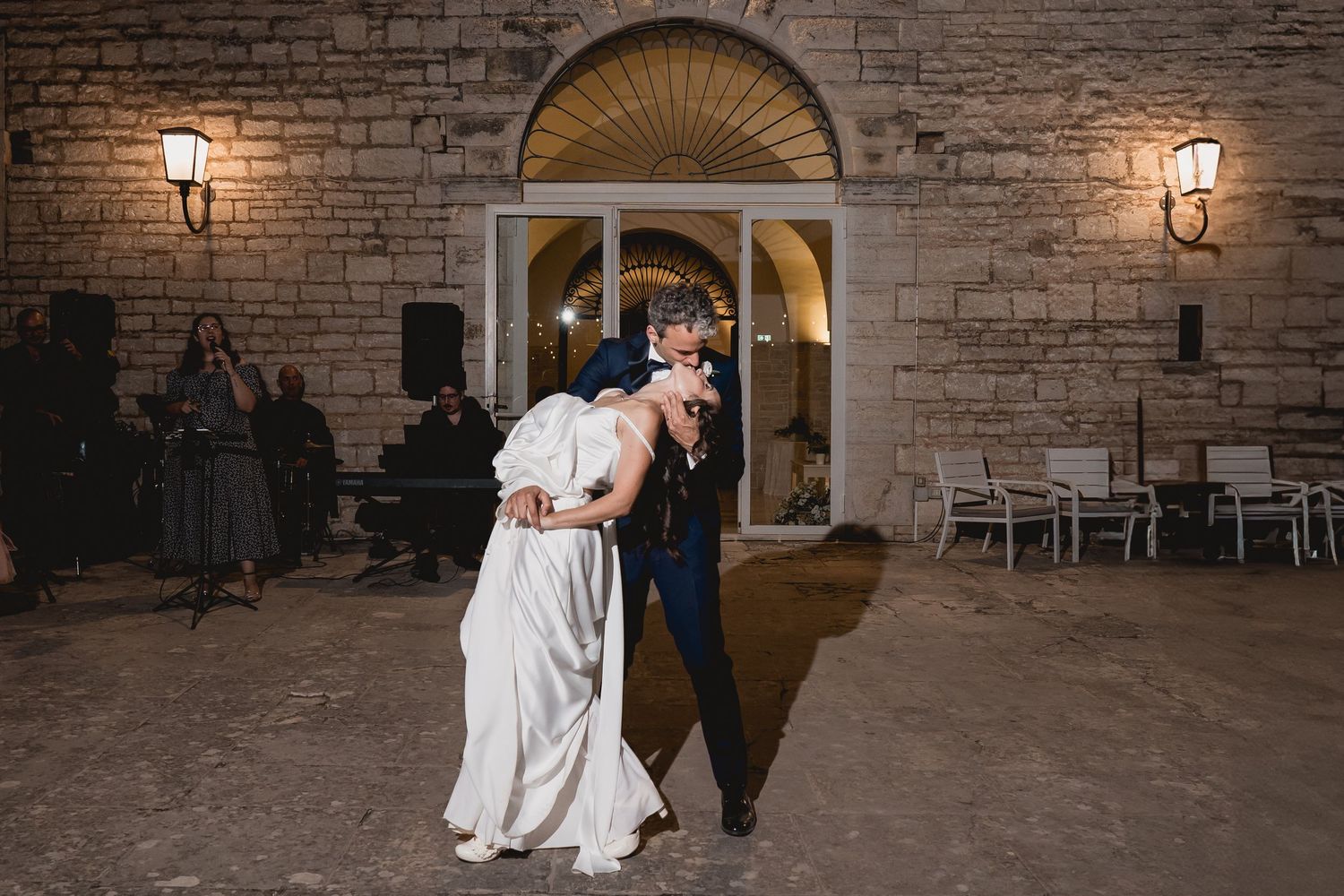 A romantic first dance moment at a wedding reception outside a stone building with glowing lanterns.