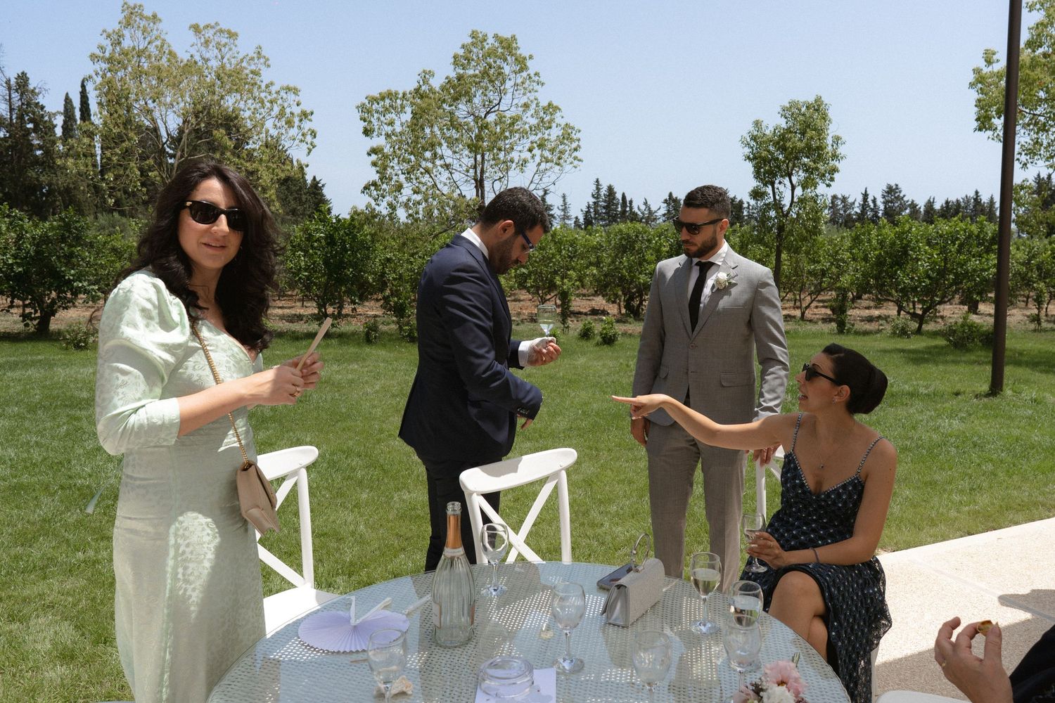 Outdoor event gathering with people mingling on a sunny day in a garden setting.