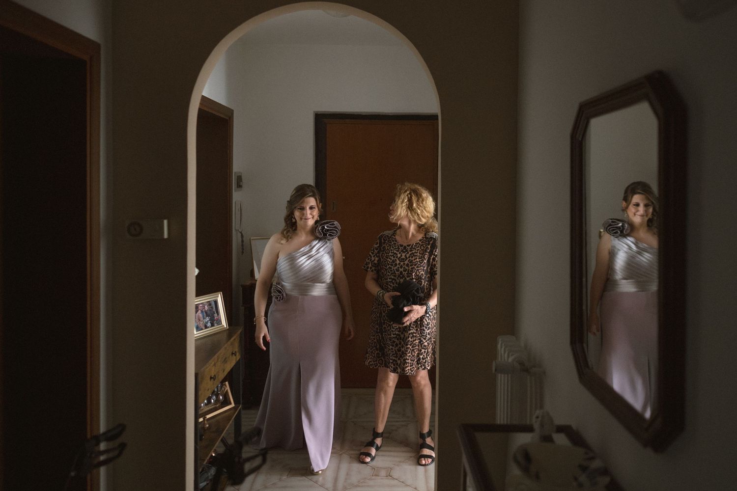 A wedding dress hangs in a doorway while being photographed in natural light.