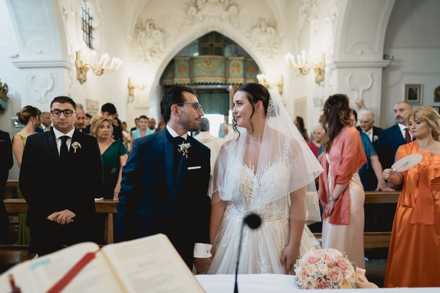 A wedding ceremony unfolds in a beautiful church with vaulted ceilings and elegant decor.