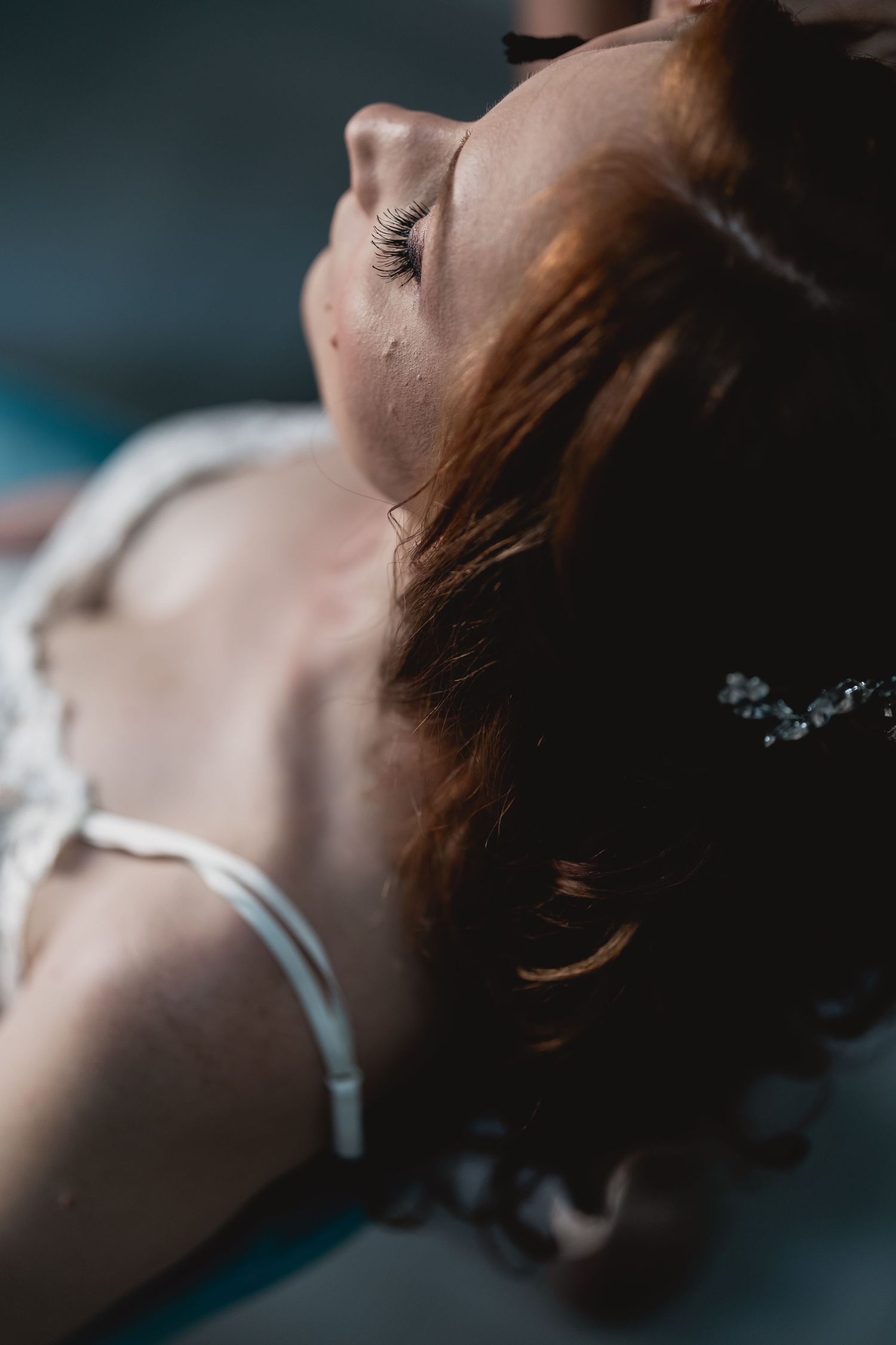 Artistic close-up portrait showing delicate details of bridal jewelry and makeup.