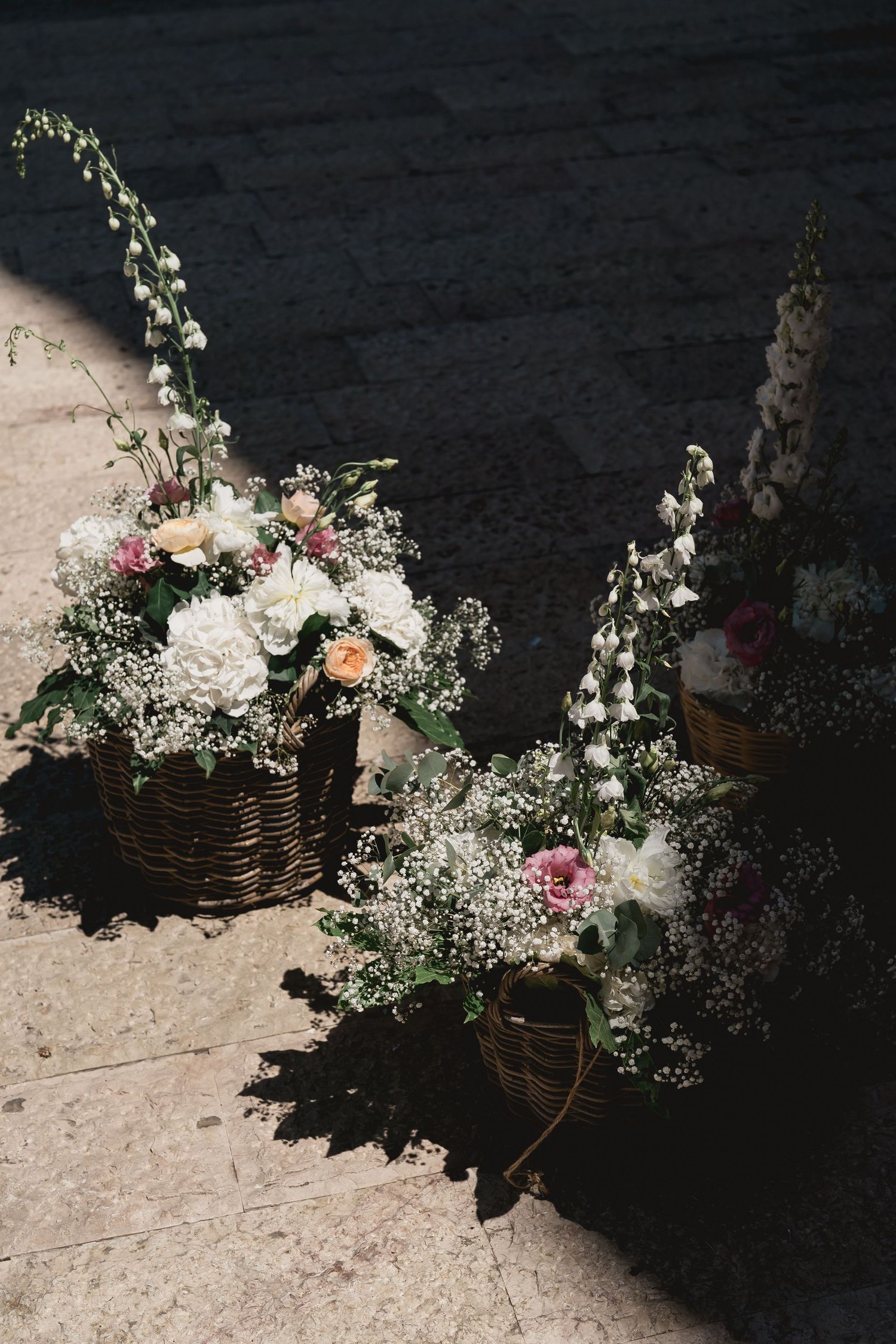 Rustic floral arrangements in wicker baskets featuring white flowers and delicate greenery.