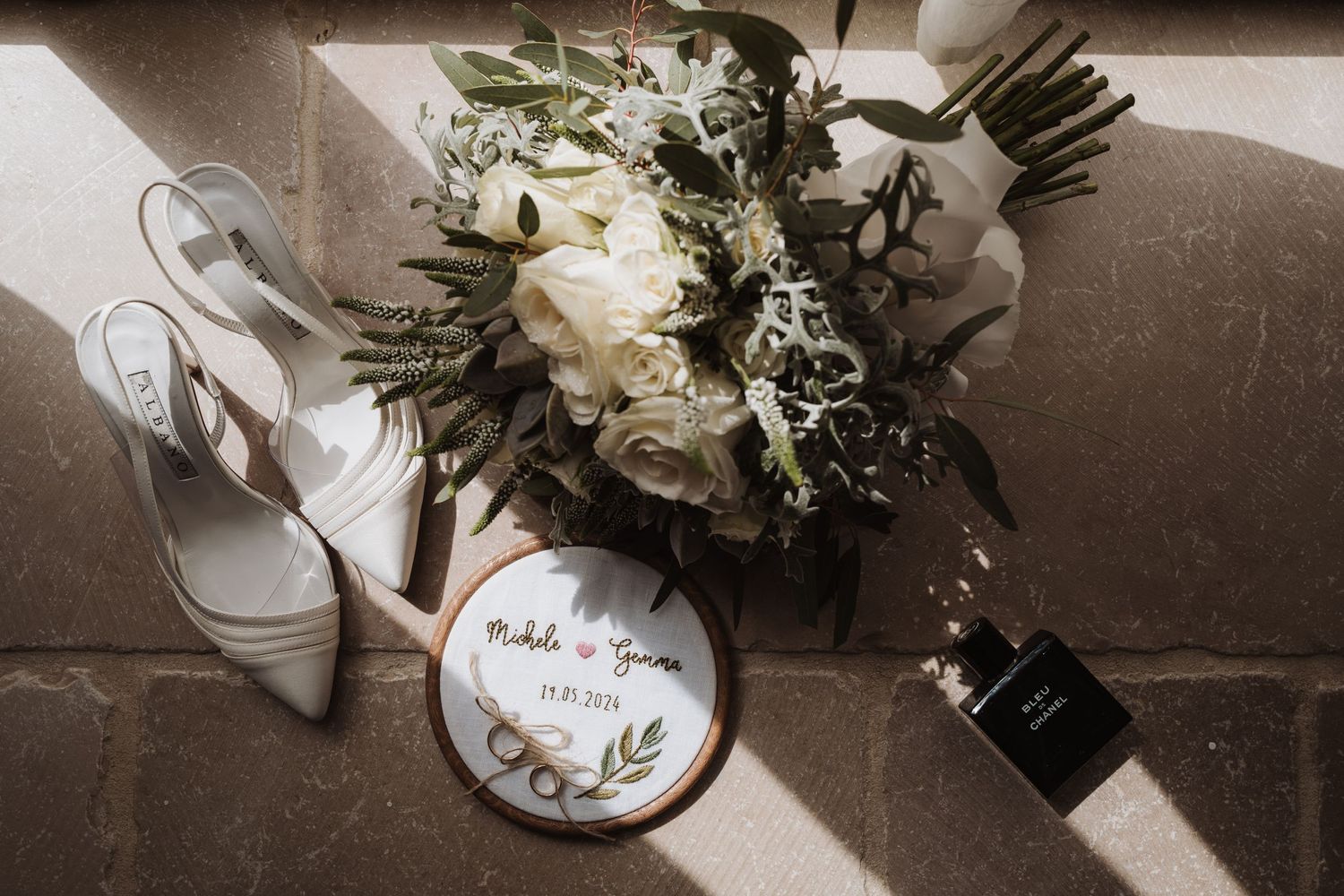 Wedding details including white shoes, floral bouquet and a decorative circular sign.