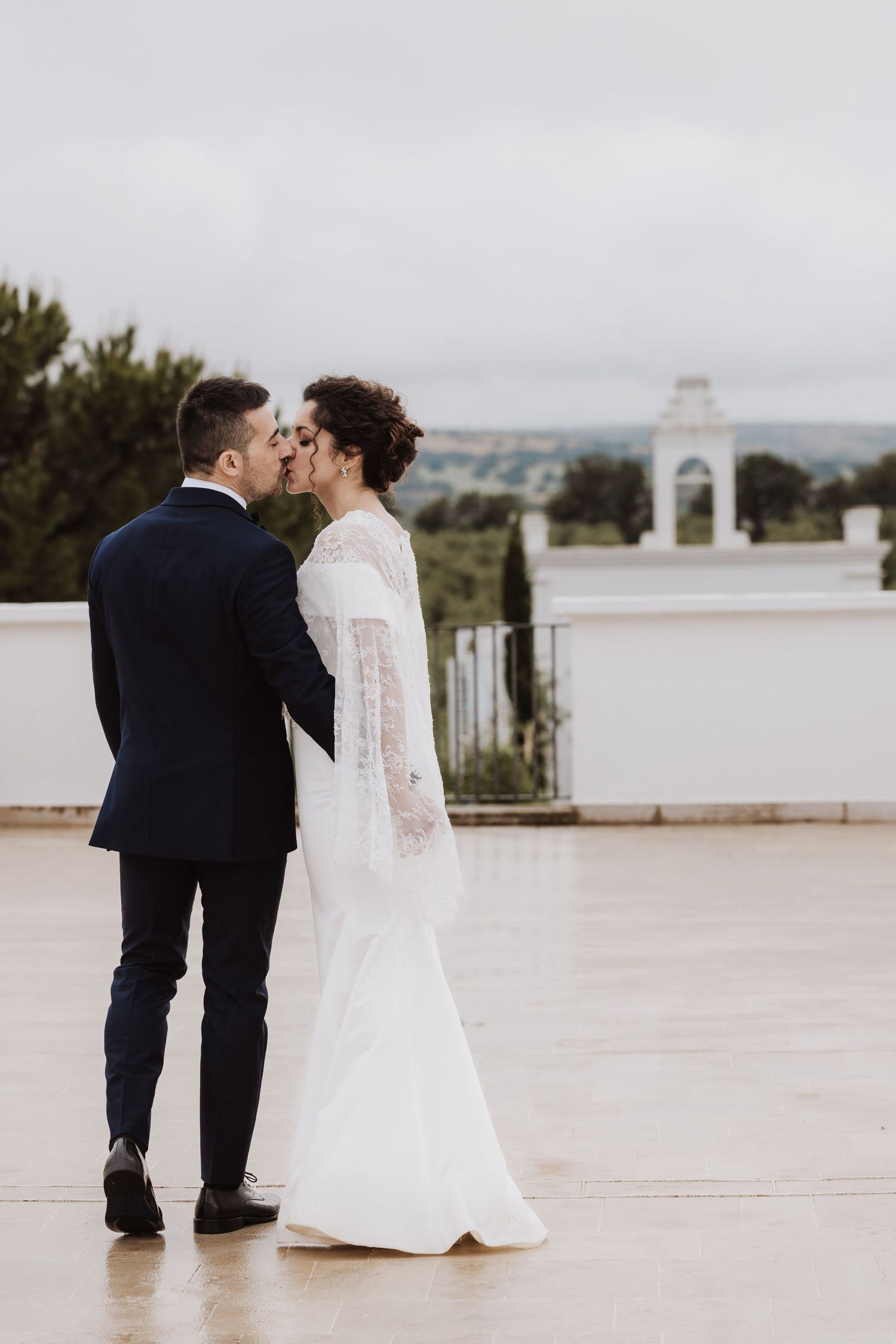 Intimate wedding moment captured on a terrace with white architecture in the background.