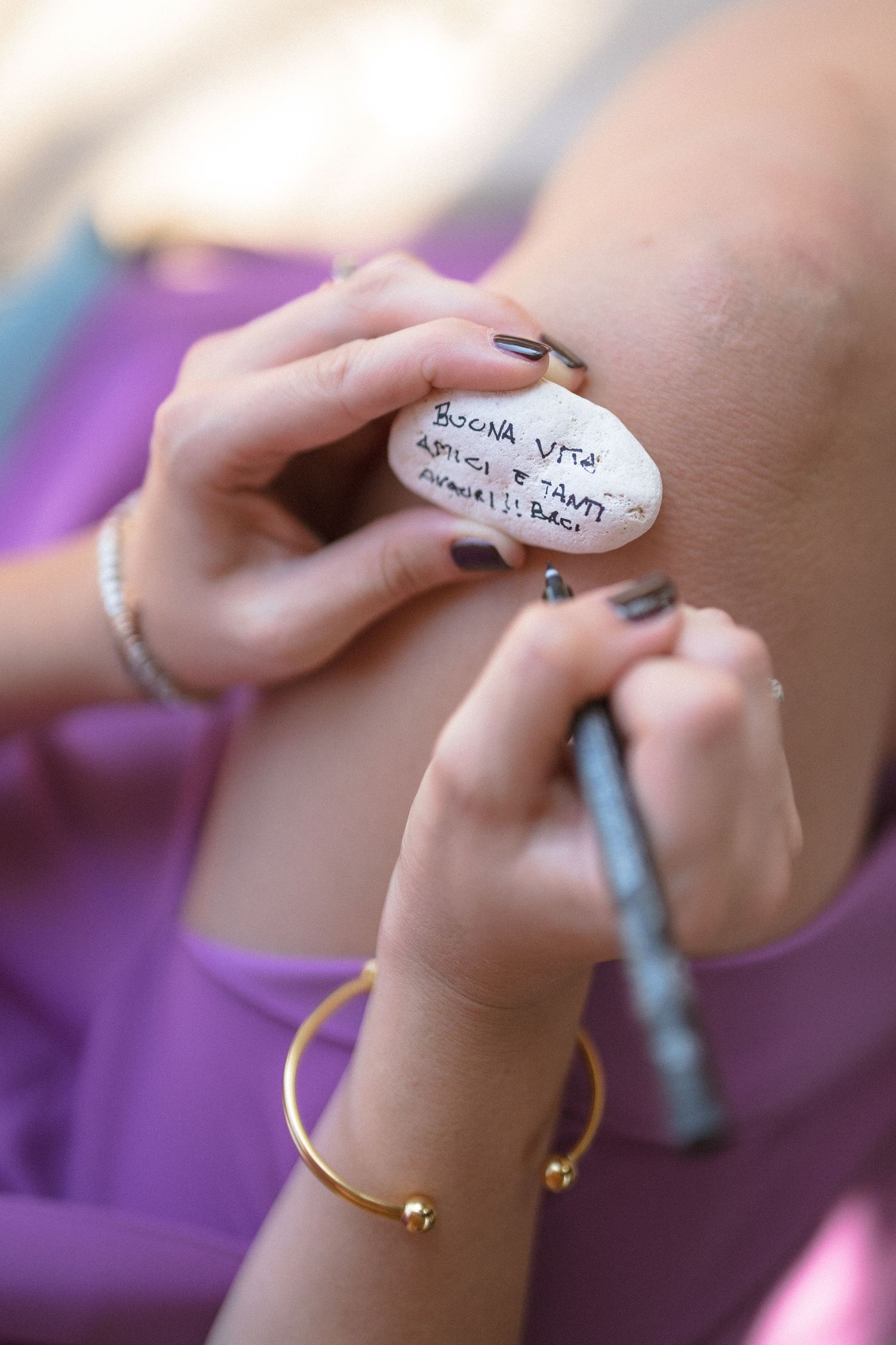 Close-up of hands writing on a surface with purple tones in the background.