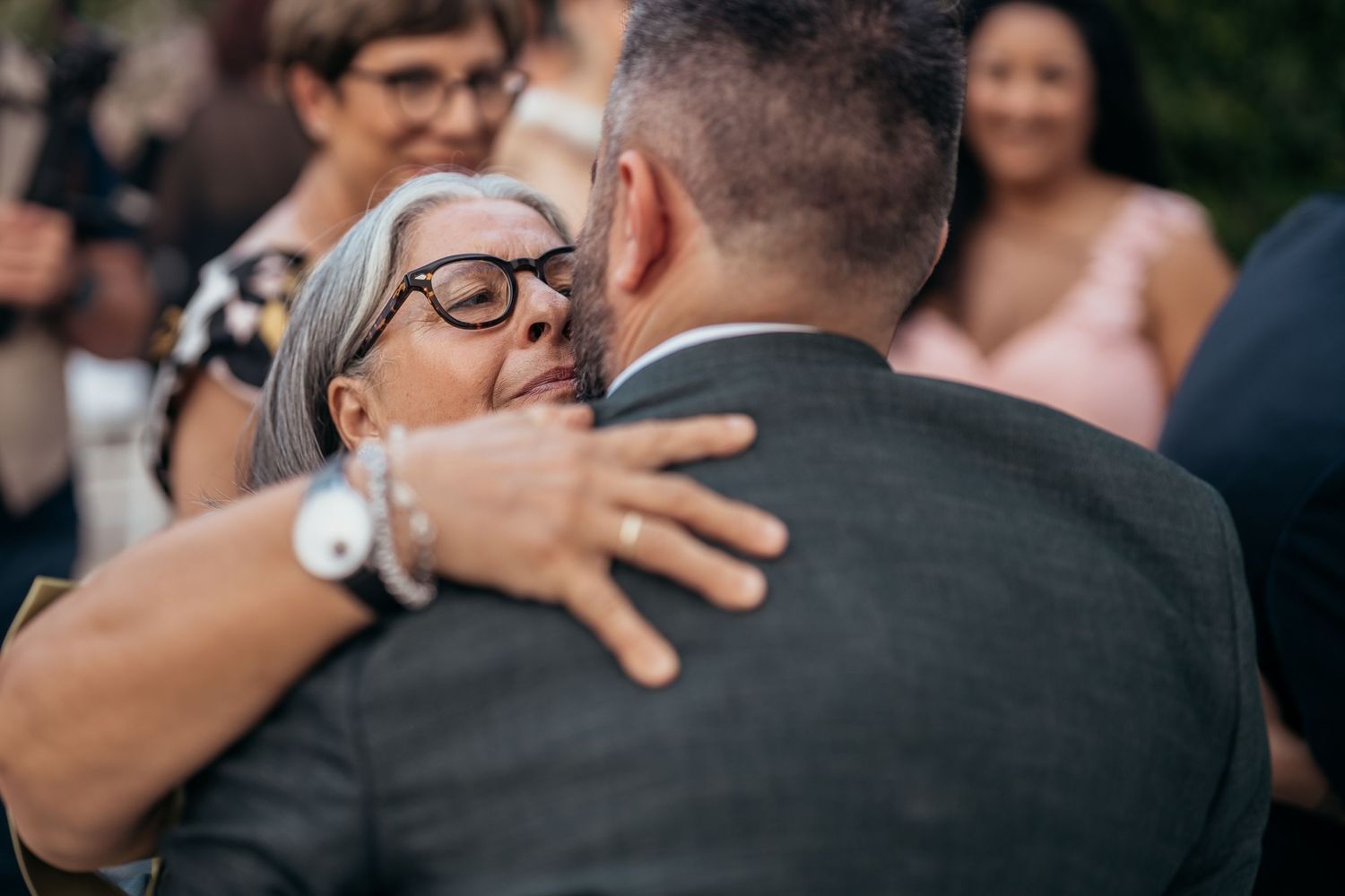 An emotional embrace shared during a wedding celebration outdoors.