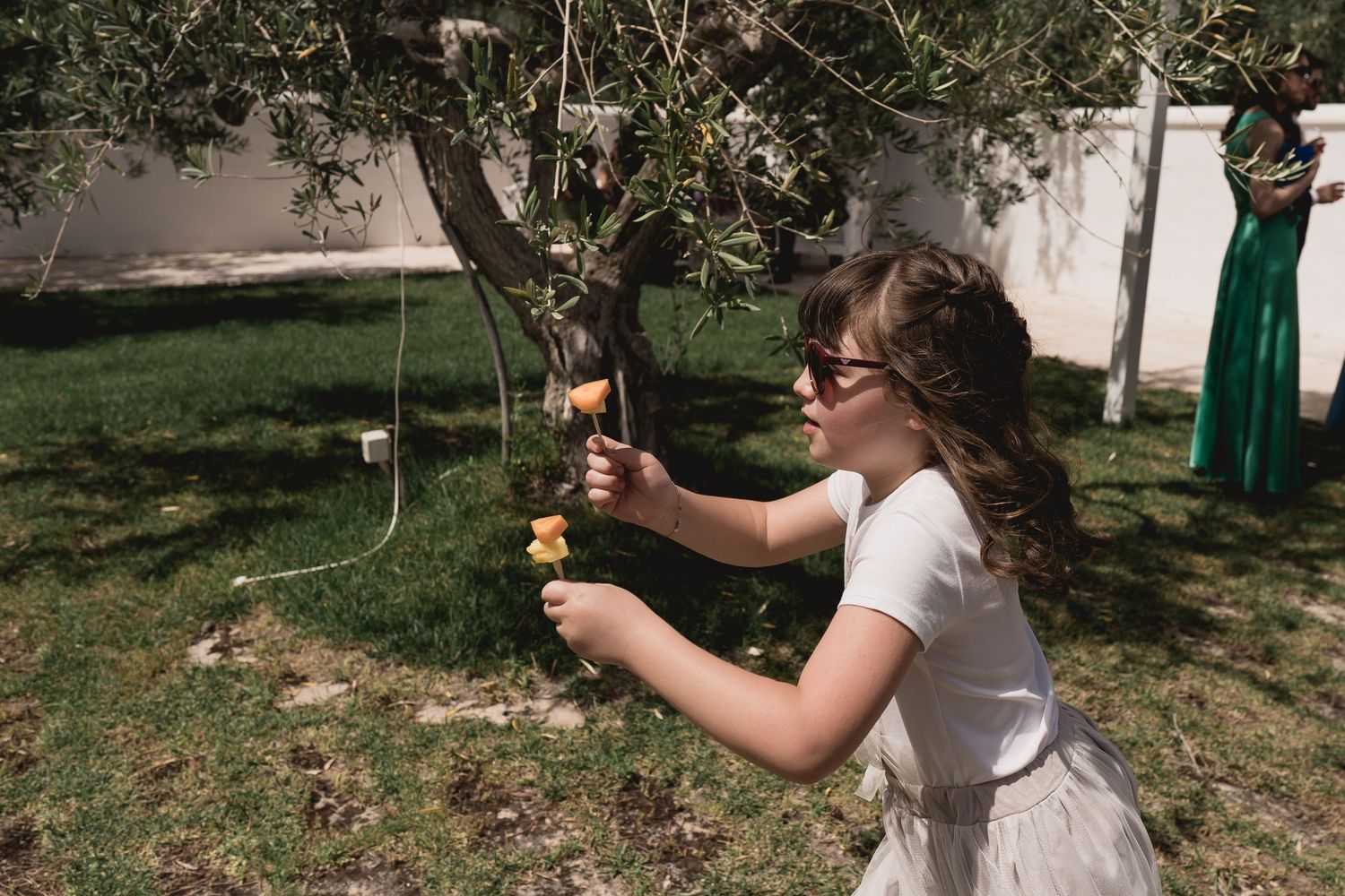 Person in white dress playing with bubbles in sunny garden setting.