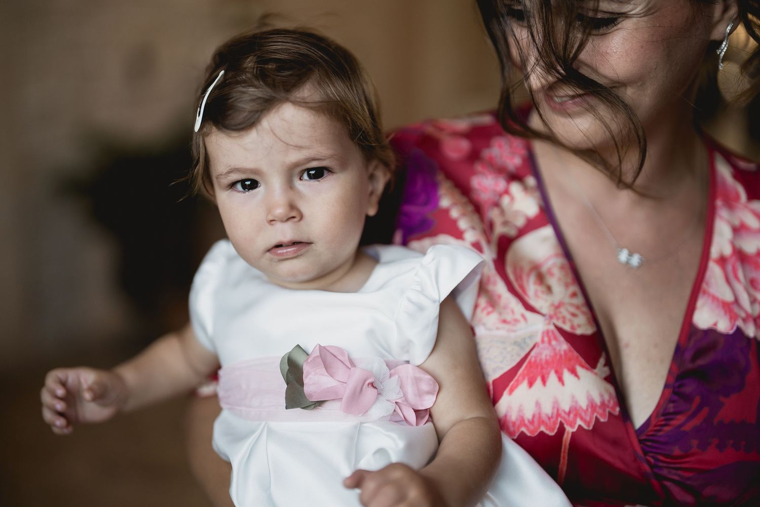 Close-up of a toddler wearing a white dress with pink bow detail.