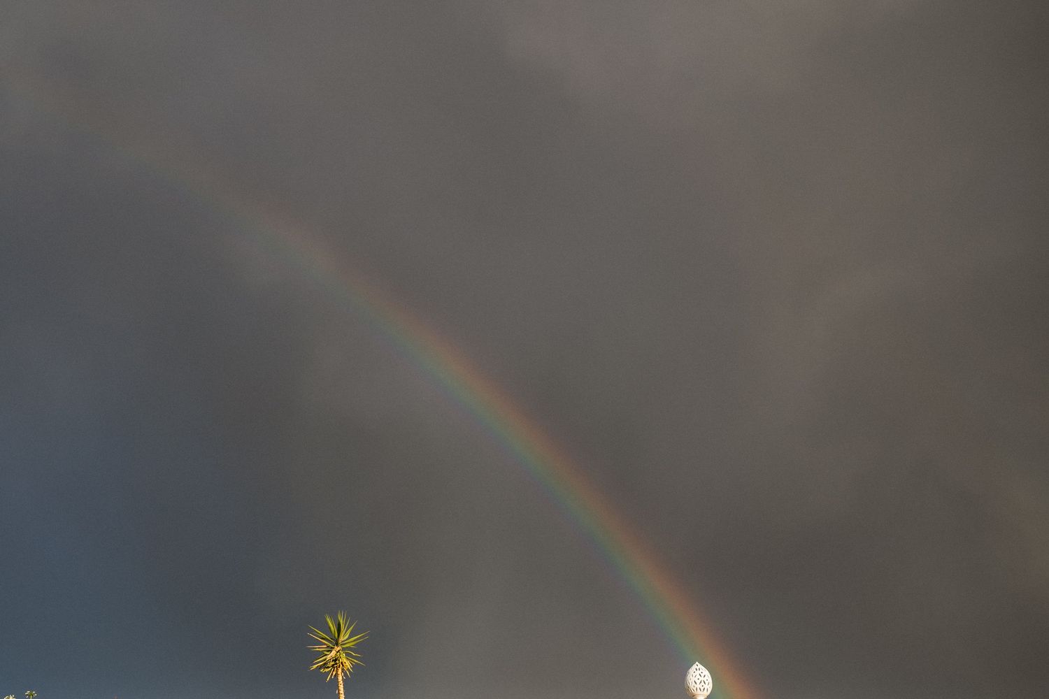 Beautiful rainbow arches across a dramatic stormy sky during an outdoor wedding celebration.