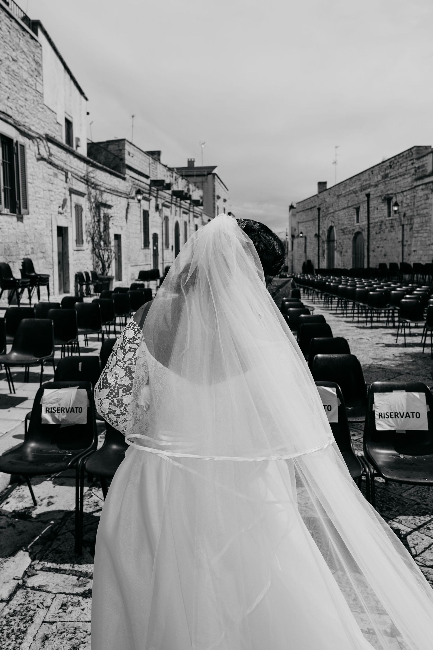 Black and white image of wedding dresses displayed against rustic stone buildings and outdoor seating.