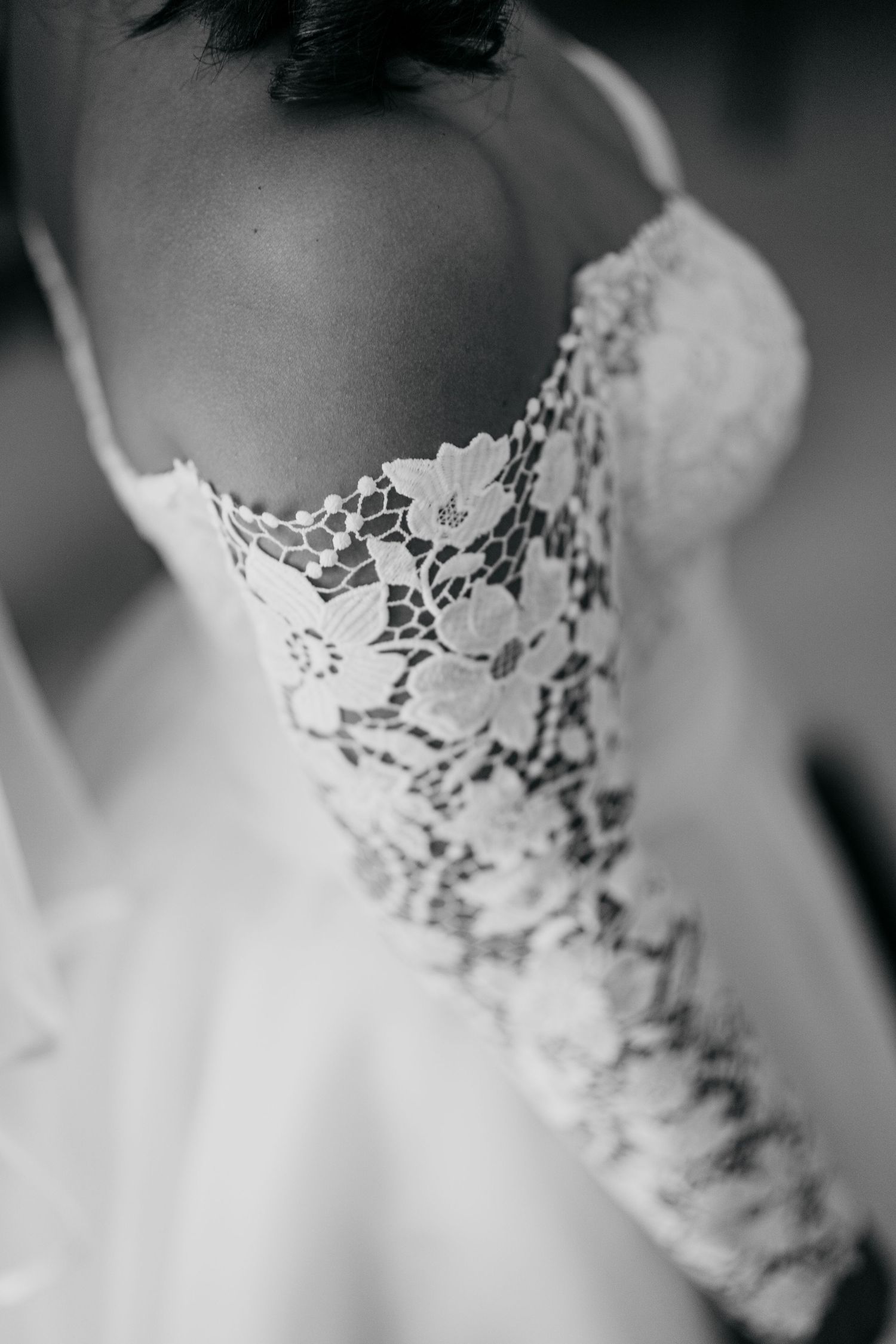 Black and white close-up of intricate floral lace details on a wedding gown.