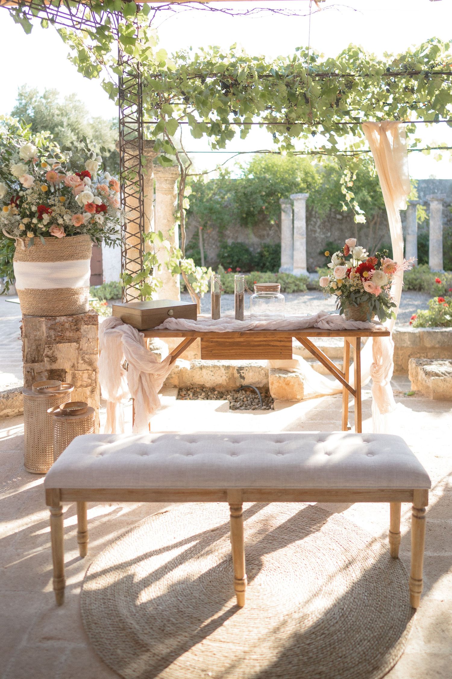 Rustic wooden benches line a sun-dappled outdoor wedding ceremony space.