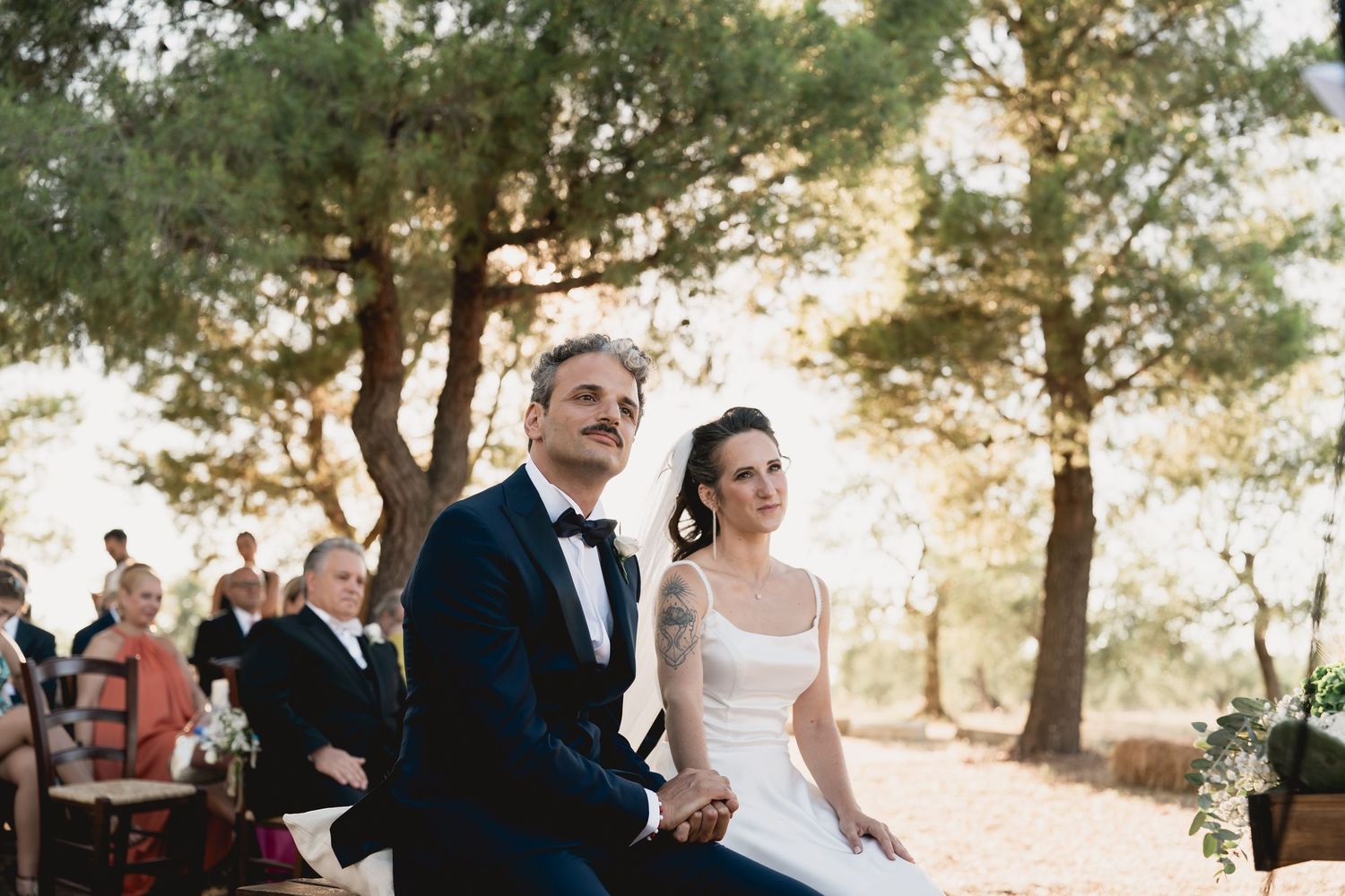 A couple shares a joyful moment during their outdoor wedding ceremony at sunset.