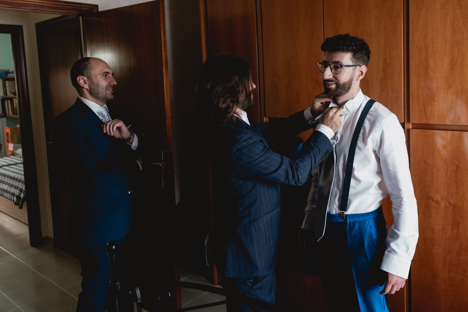 Wedding preparation scene showing final adjustments being made to formal attire.